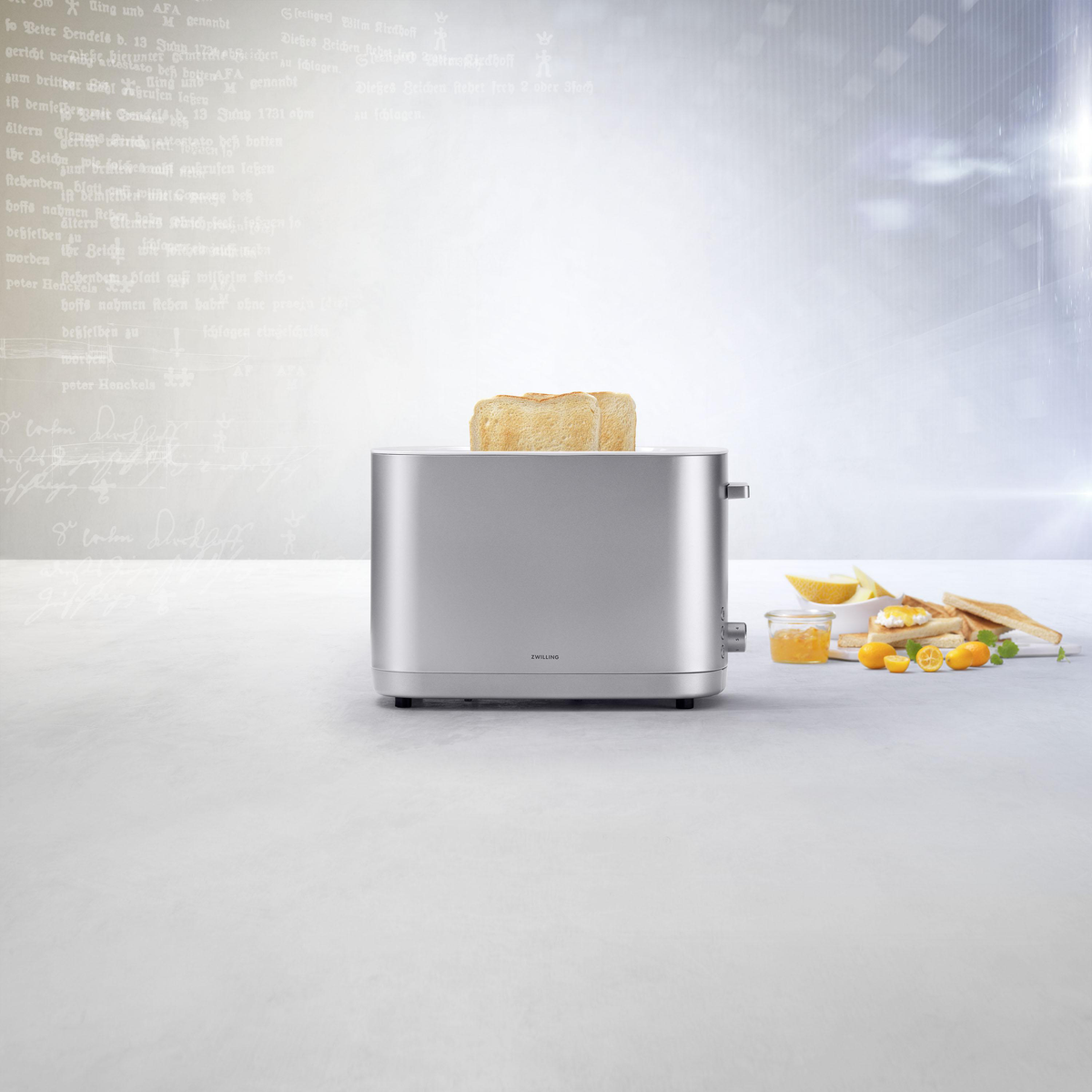 Srebrny toster z chlebem w środku. Tło to miękki, rozmyty obraz z plasterkiem cytryny i dżemem.
