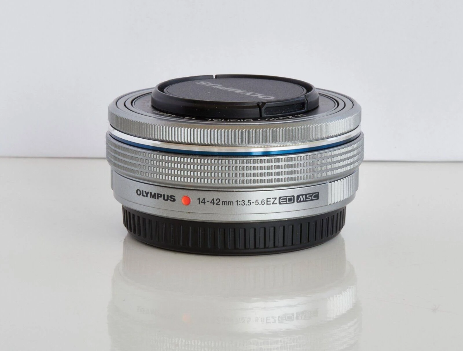 Een Olympus cameralens, zilver en zwart, met een lensdop.