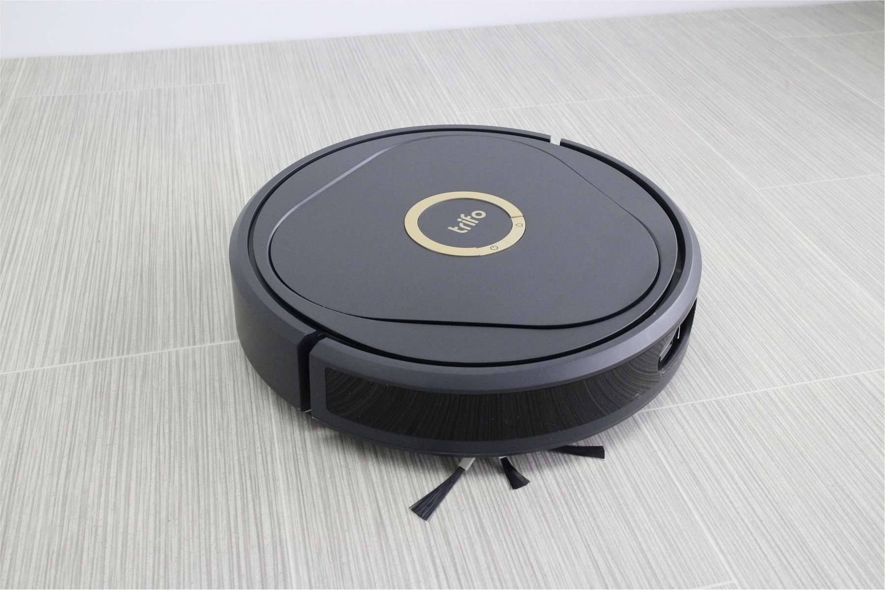 Szary robot sprzątający na podłodze z płytek.