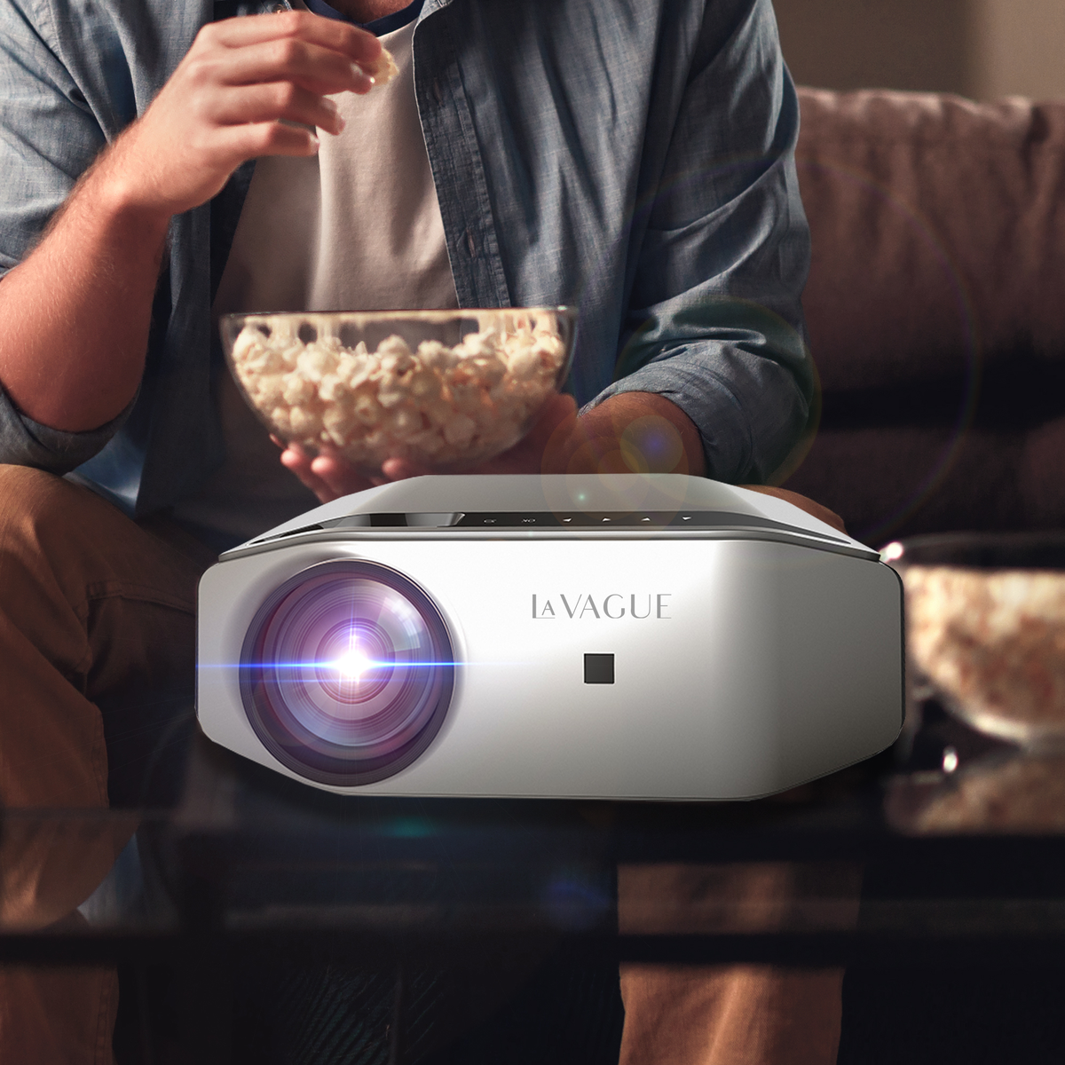 Un projecteur projetant de la lumière, avec une personne tenant du pop-corn en arrière-plan.