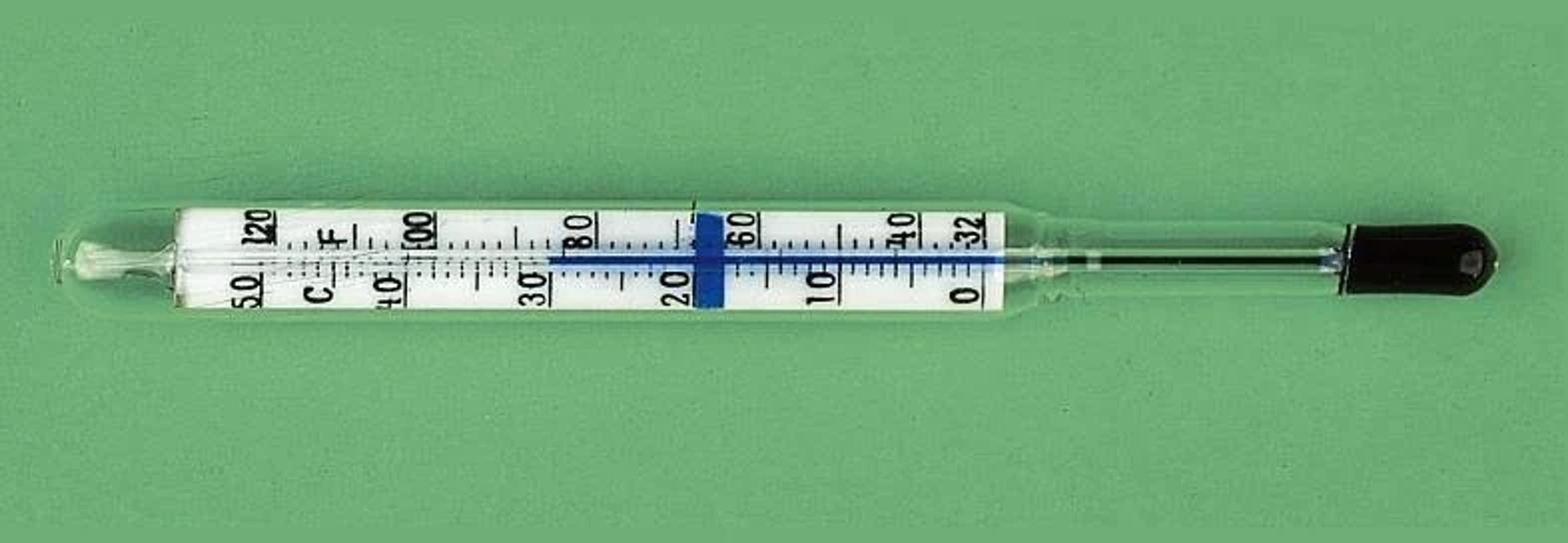 Un termómetro de vidrio transparente sobre un fondo verde, con líquido en su interior y marcas de temperatura en Celsius y Fahrenheit.