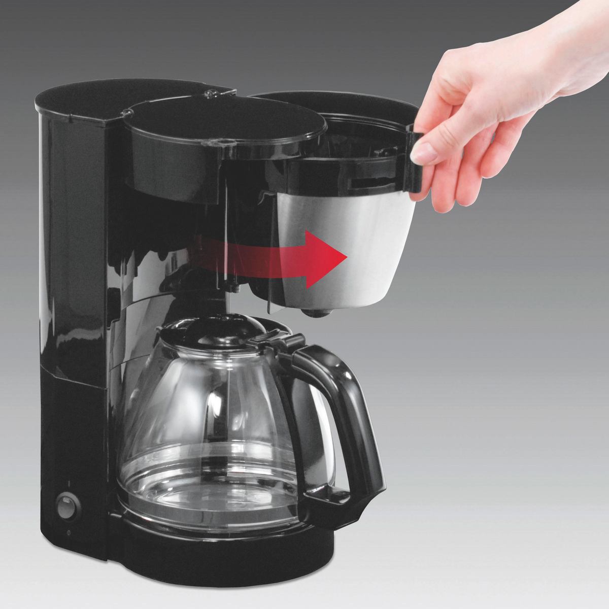 Czarny ekspres do kawy ze szklaną karafką. Ręka wyciąga uchwyt filtra, czerwona strzałka.