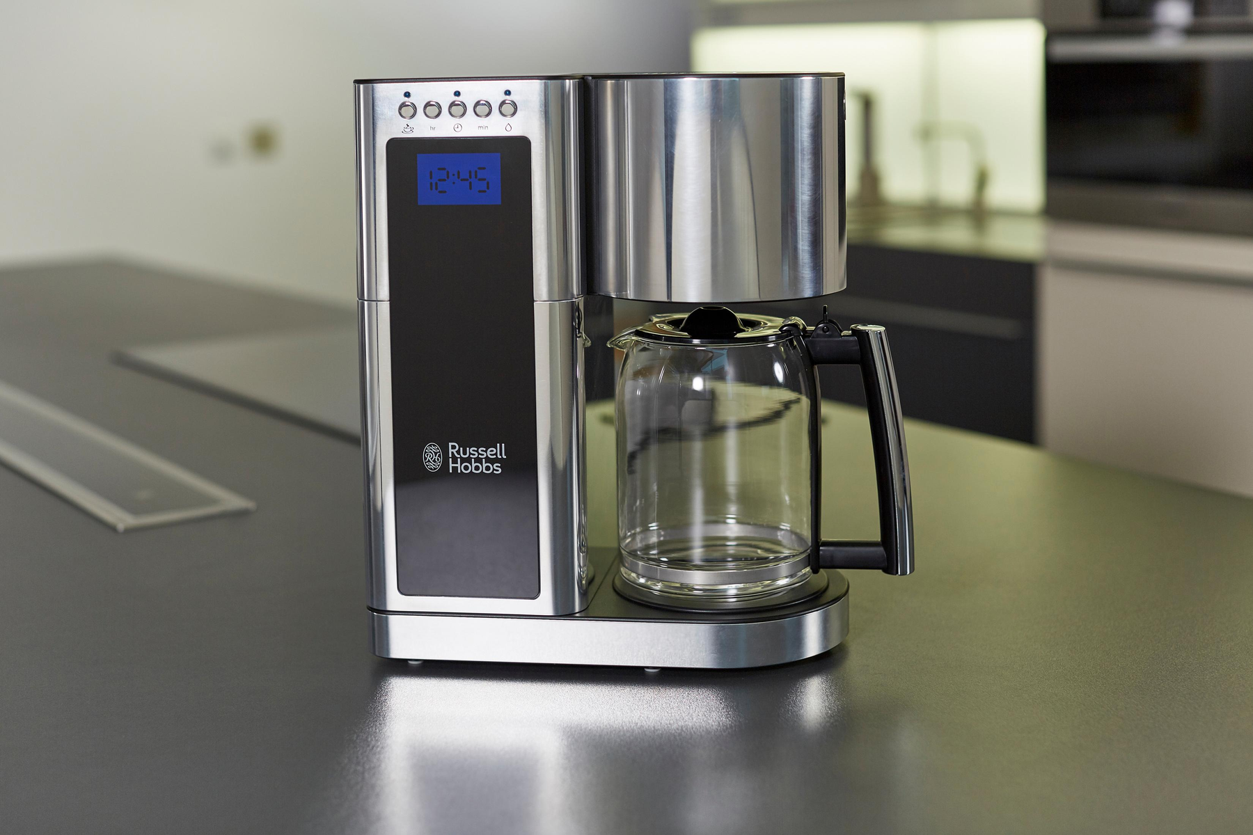 Caffettiera argento e nera con display digitale. Vista tavolo, che mostra la caffettiera e la caraffa.