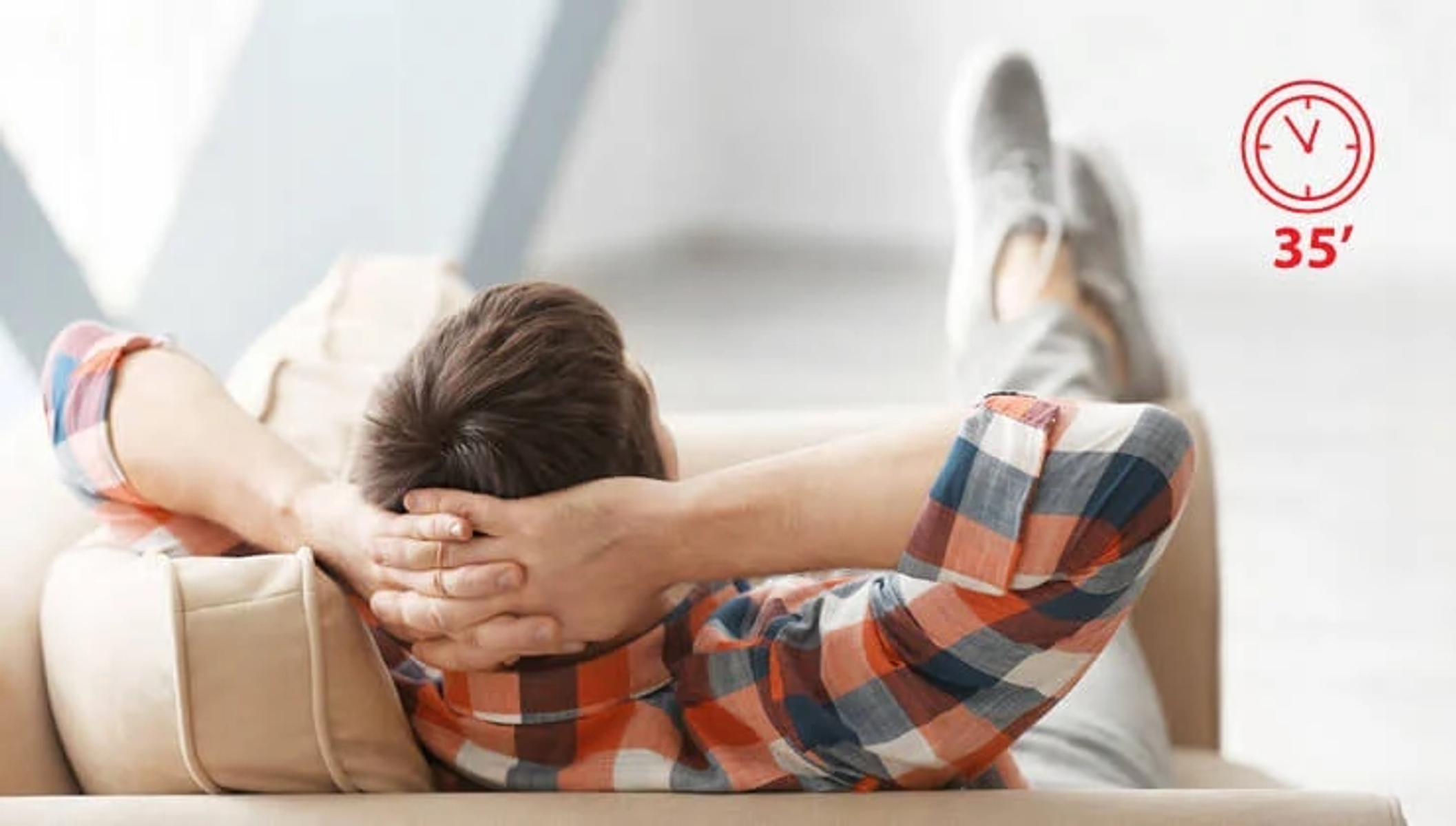 Ein Mann entspannt sich auf einem Sofa, Hände hinter dem Kopf. Eine Uhr zeigt 35 Minuten.