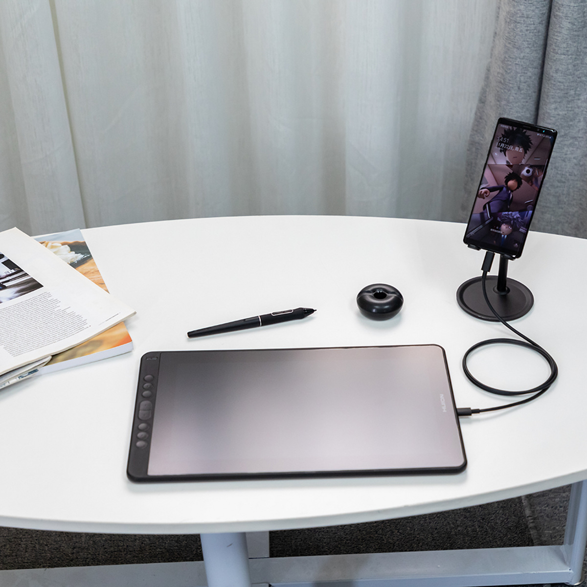 Tablet, pen, and smartphone on a white table. Phone on stand, drawing tablet.