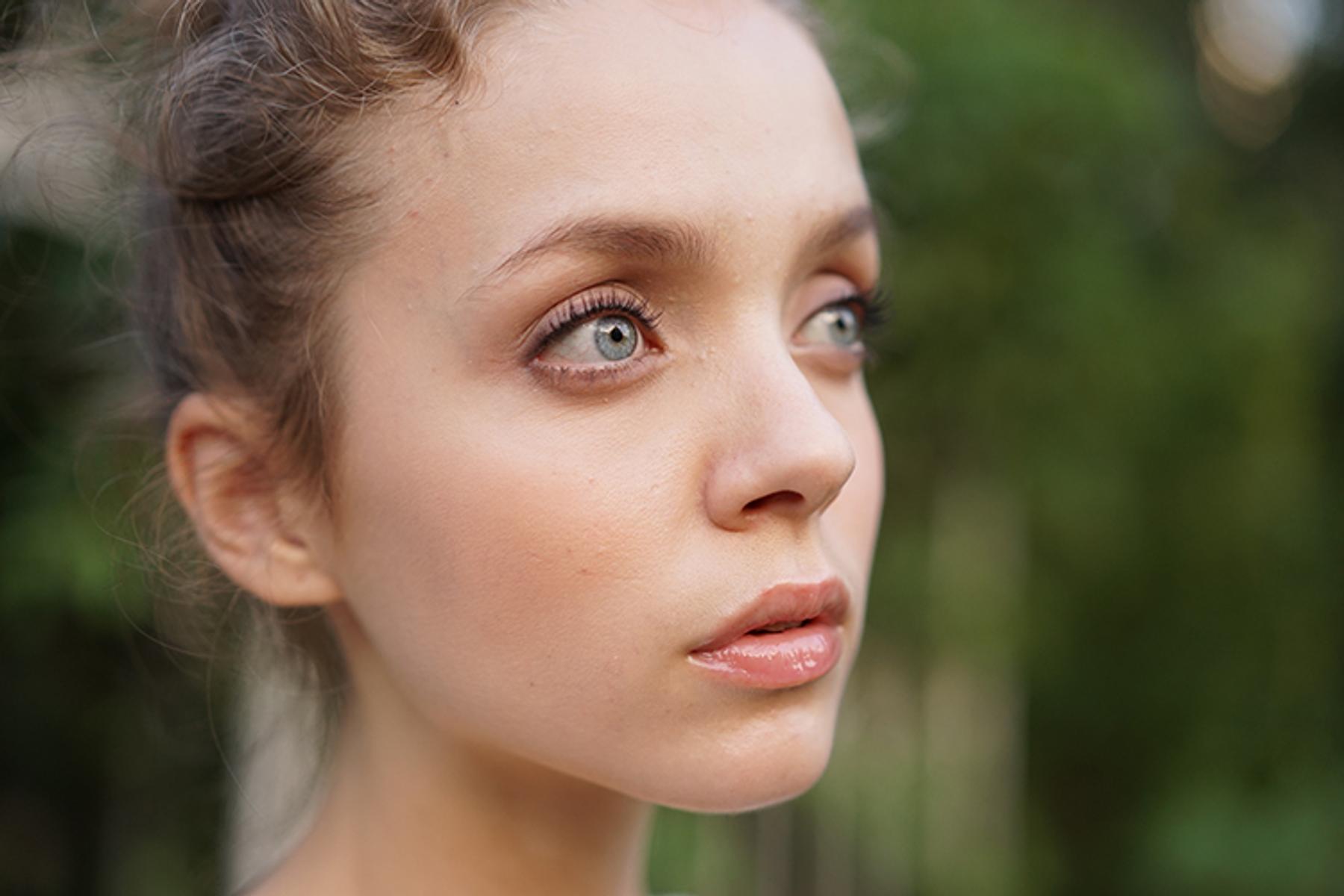 Zbliżenie twarzy młodej kobiety, patrzącej w bok. Jasna skóra, niebieskie oczy, delikatny wyraz twarzy.