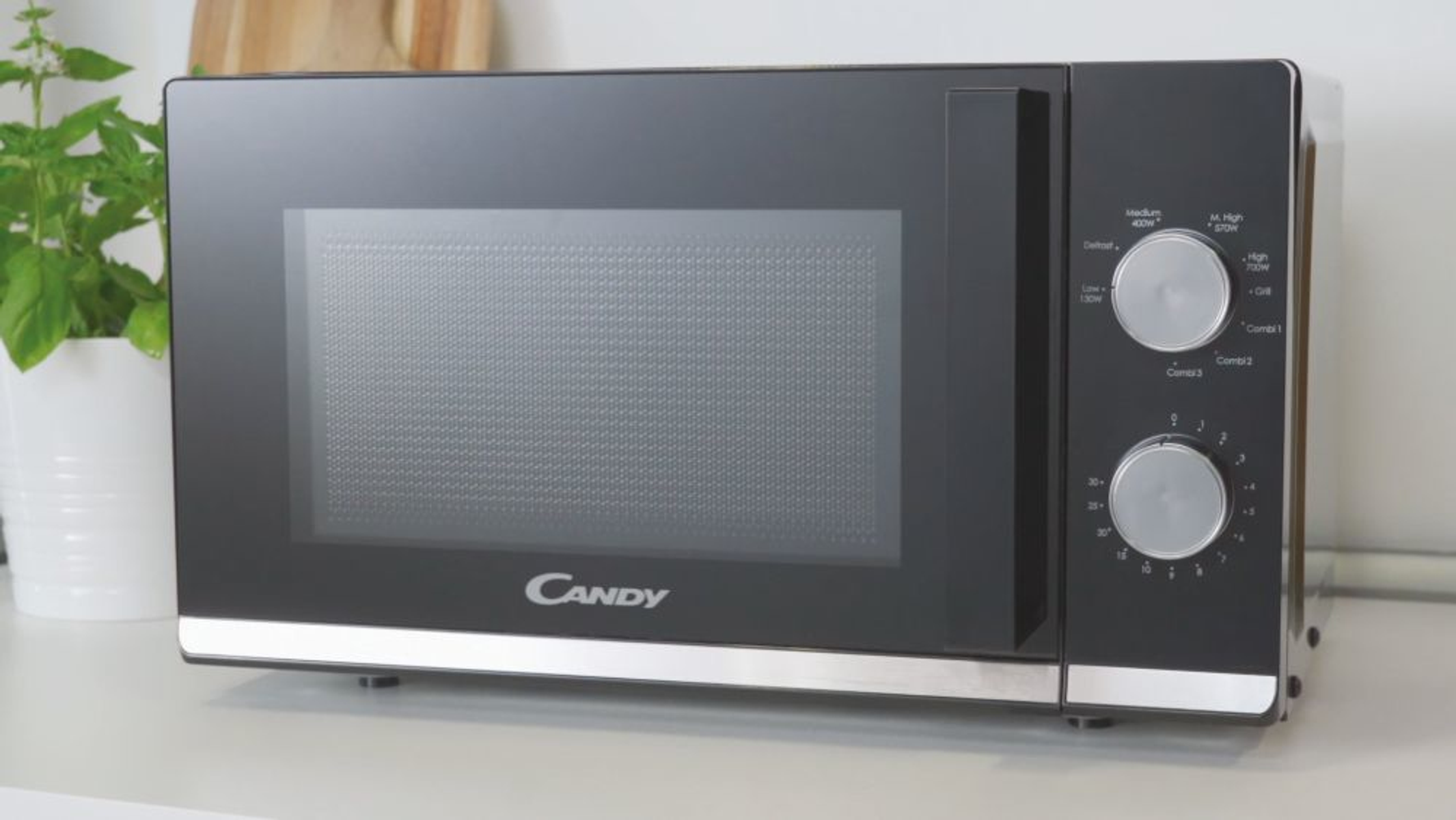 Czarny piekarnik mikrofalowy z pokrętłami i szklanymi drzwiami. Marka to Candy.