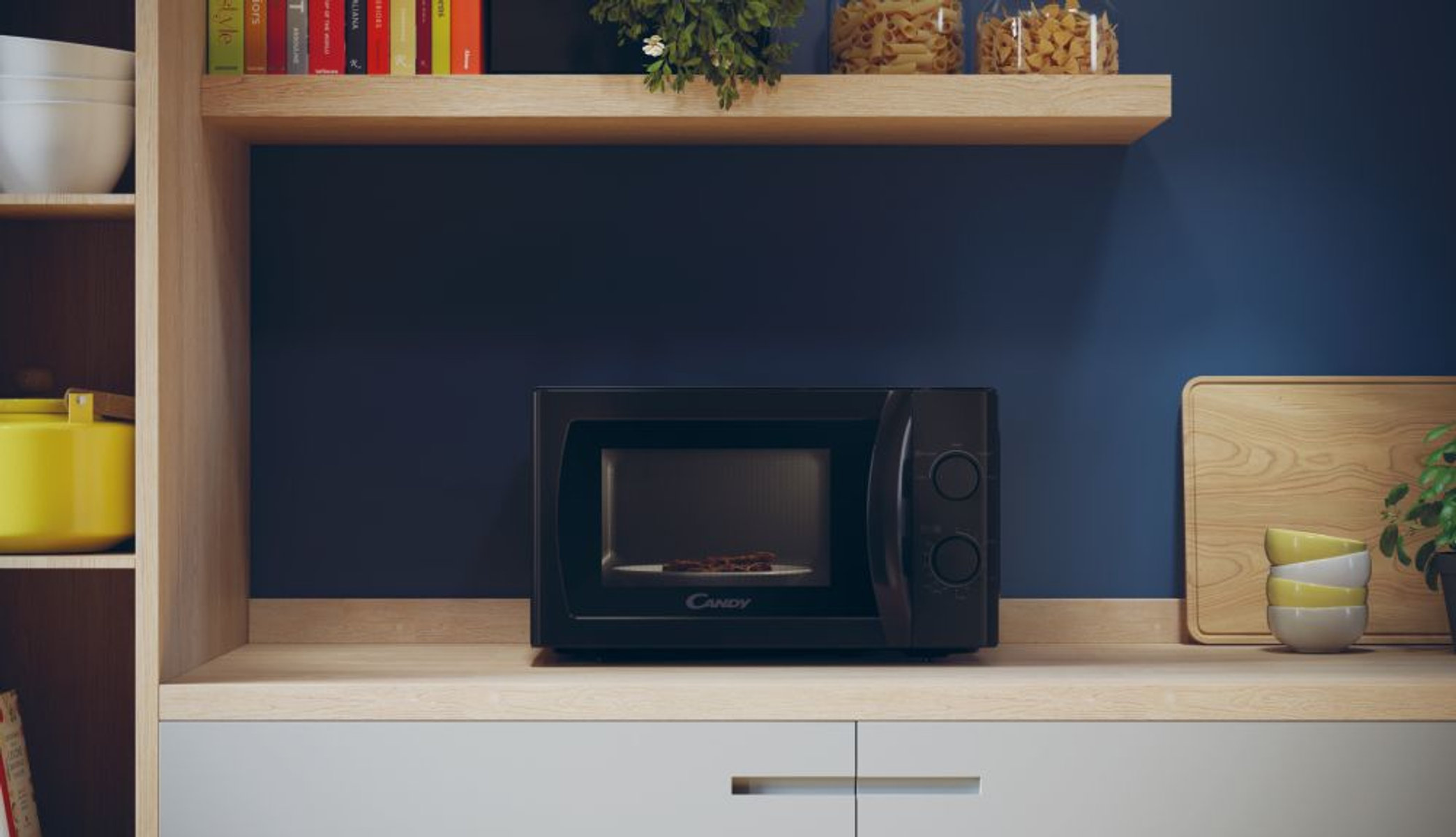 Czarna kuchenka mikrofalowa na drewnianym blacie. Za nią ciemnoniebieska ściana i drewniane półki.