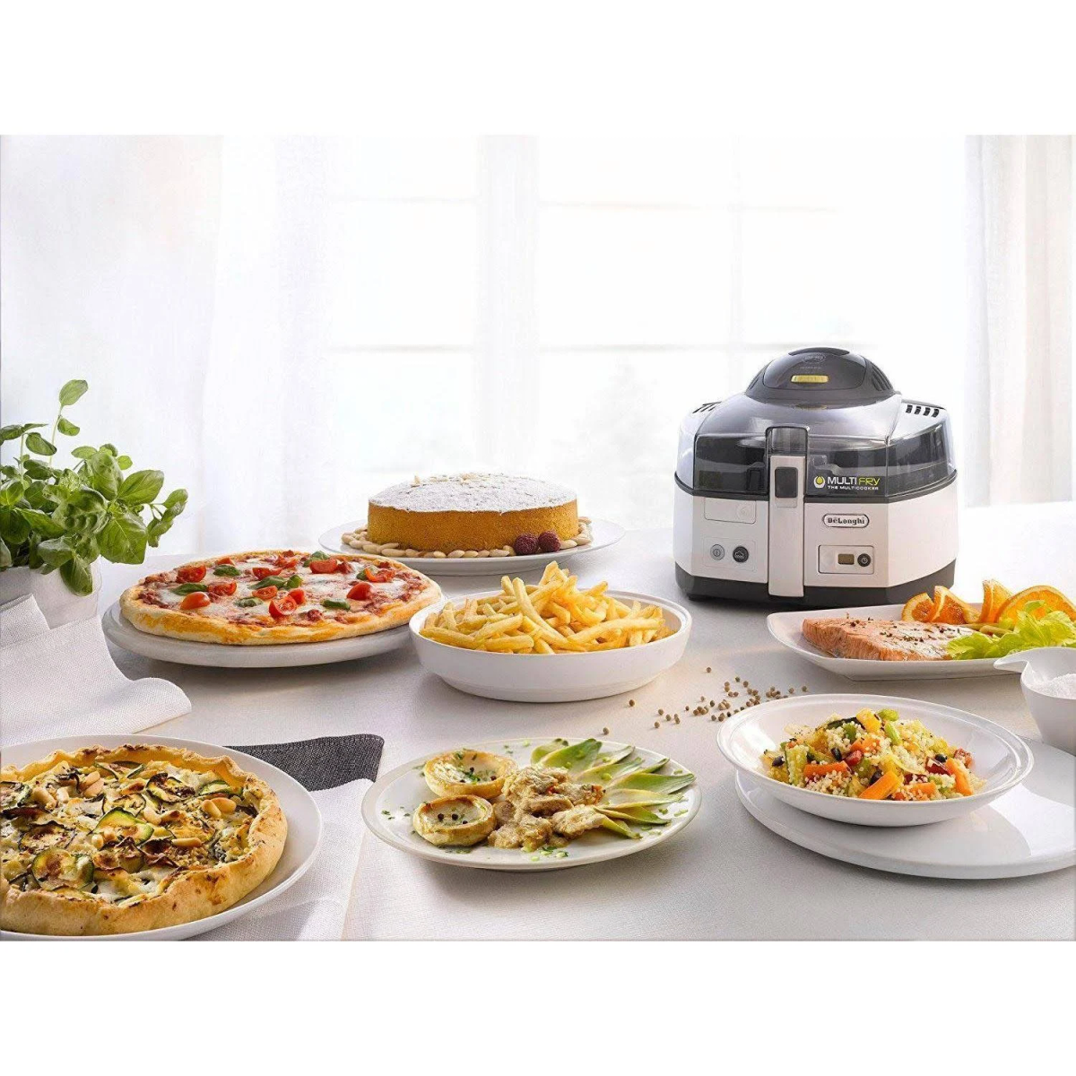 Mesa con pizza, pastel, patatas fritas, salmón y otros platos. Freidora de aire a la derecha.