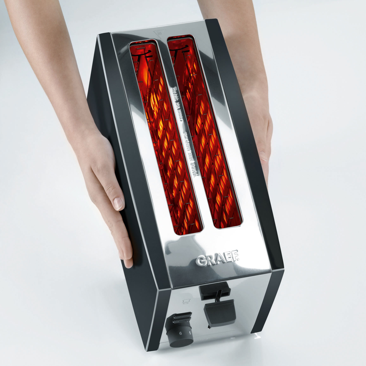 Mani che tengono un tostapane nero e argento con elementi riscaldanti rossi incandescenti.