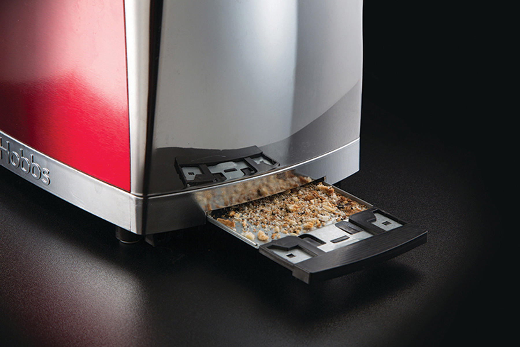 Toaster mit offener Krümelschublade, die Krümel enthält. Rote Seite sichtbar.