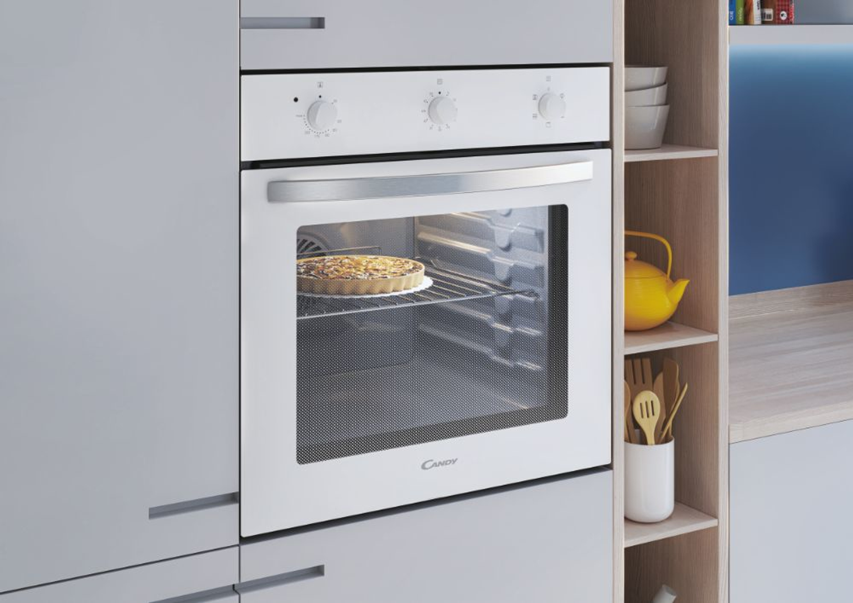 Forno bianco integrato in un mobile. Una torta è nel forno. Ci sono ripiani a destra.