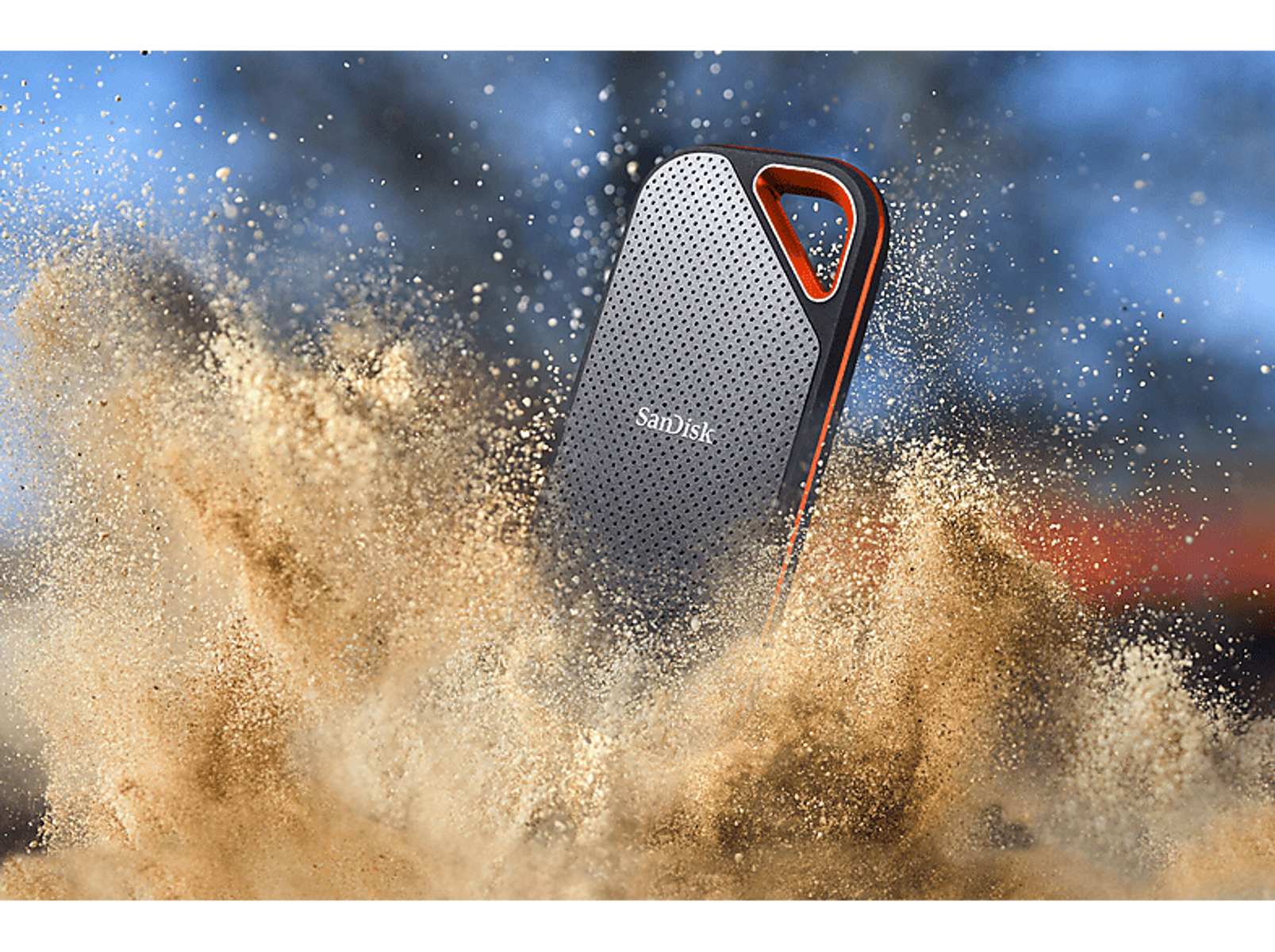 Czarny i pomarańczowy przenośny dysk twardy otoczony piaskiem, z efektem rozprysku.