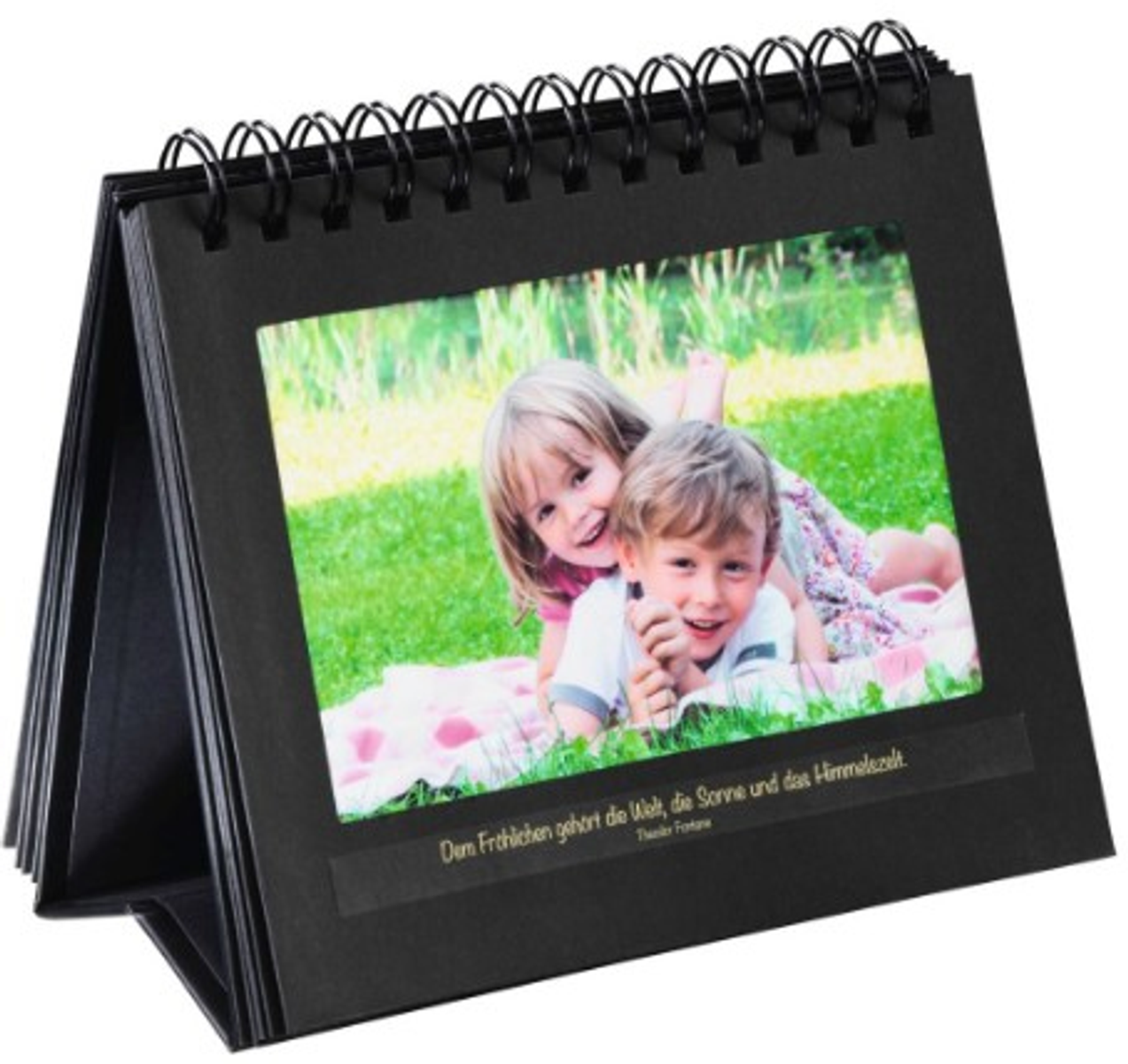Schwarzes Fotoalbum mit einem Bild von zwei Kindern. Sie lächeln und liegen auf Gras.