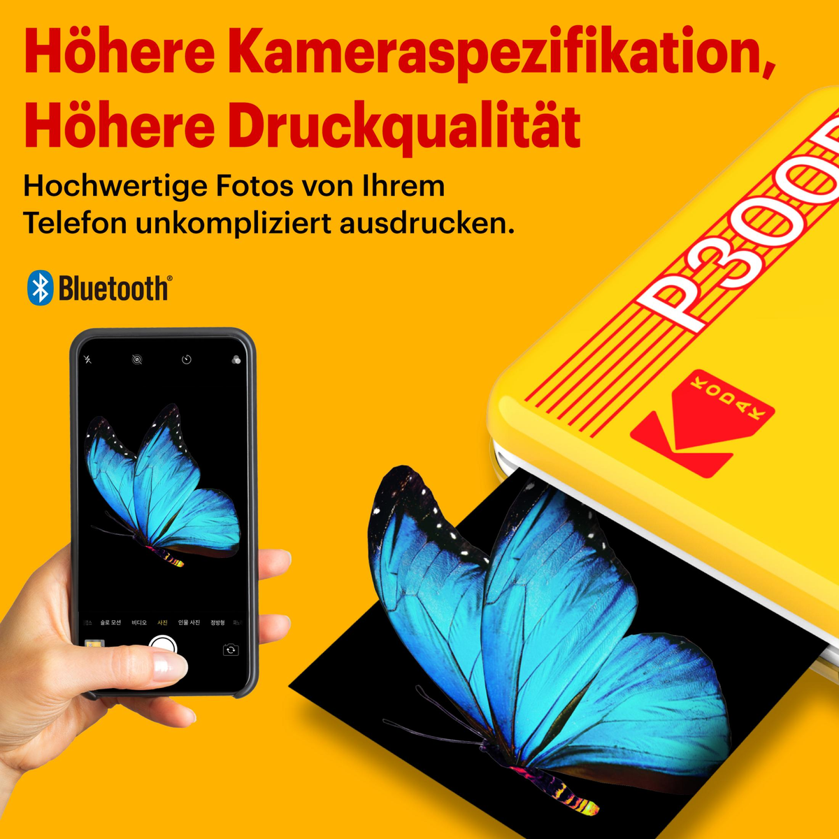 Eine Person hält ein Telefon mit einem Foto eines blauen Schmetterlings und daneben einen gelben Drucker.