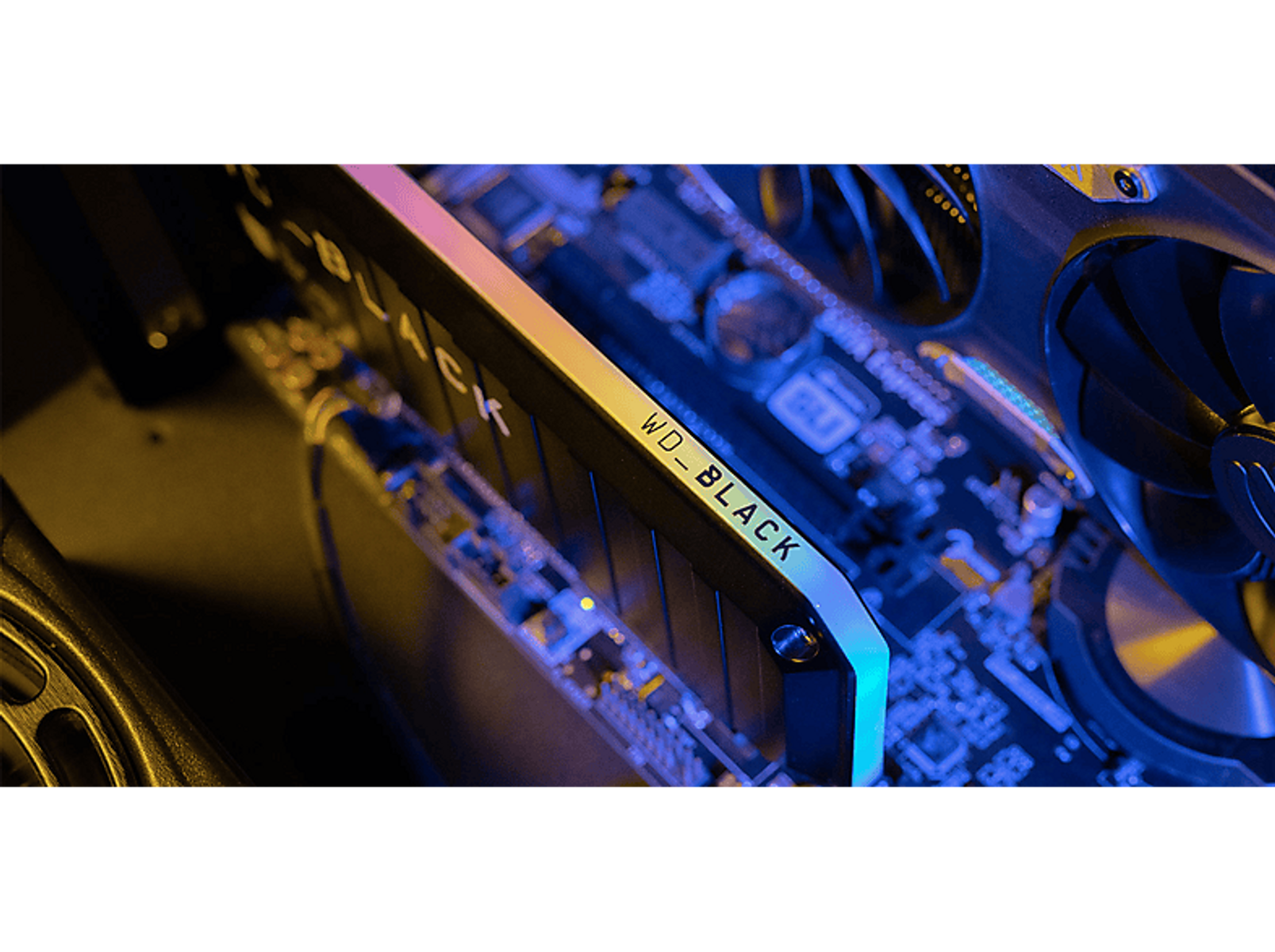 Nahaufnahme einer schwarzen WD_BLACK SSD, die in einem Computer mit blauen und gelben Lichtern installiert ist.