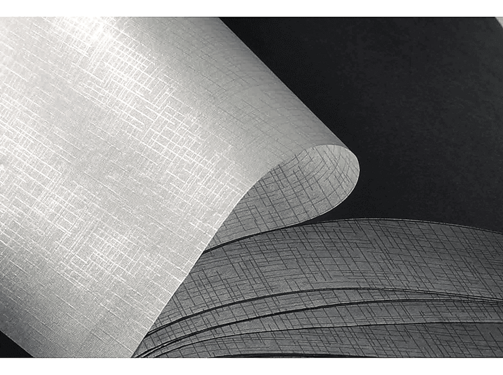 Zbliżenie zwiniętego białego i szarego papieru o fakturze. Papier ma subtelny wzór i jest złożony.