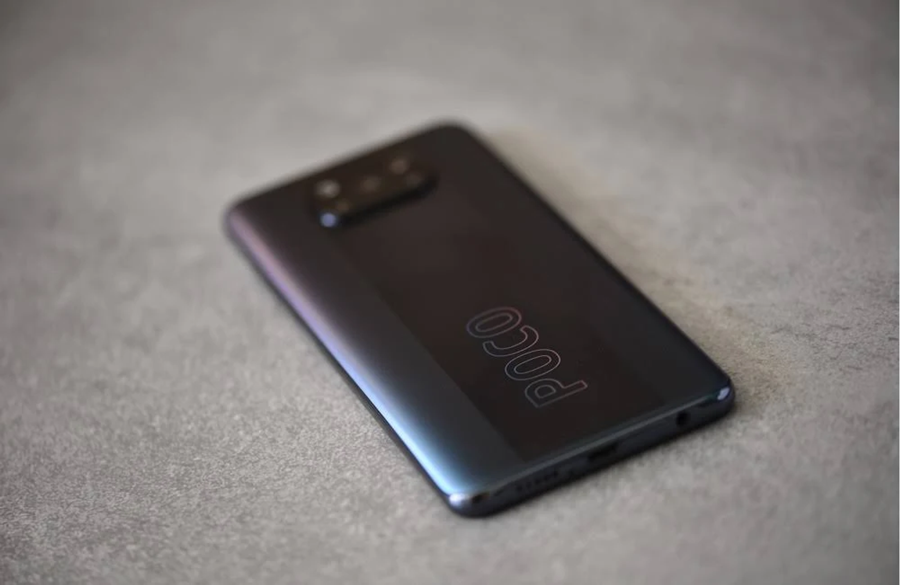 Schwarze Telefonrückseite auf grauer Oberfläche mit POCO-Branding.