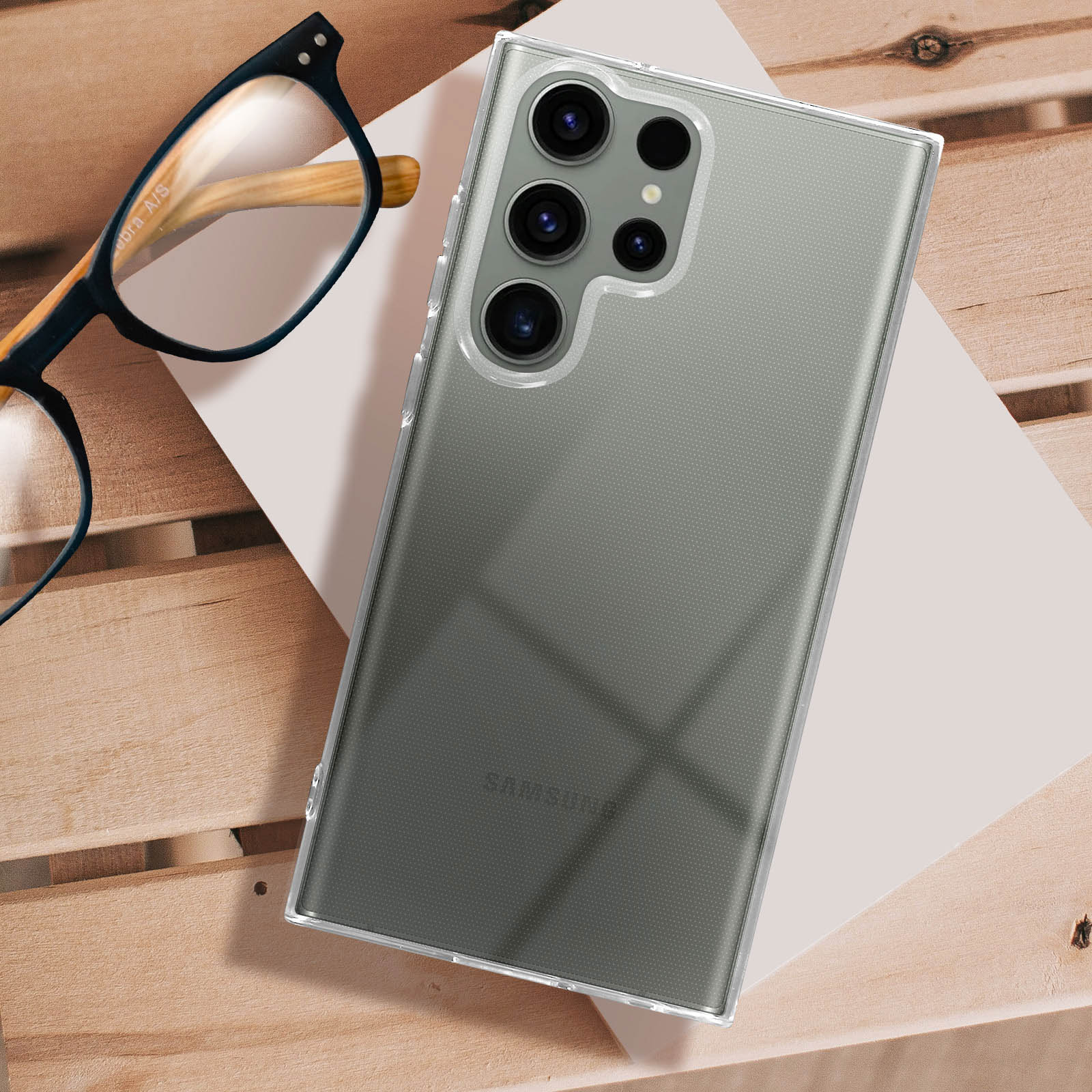 Transparante telefoonhoes op een houten oppervlak met een bril. De telefoon heeft meerdere camera's.