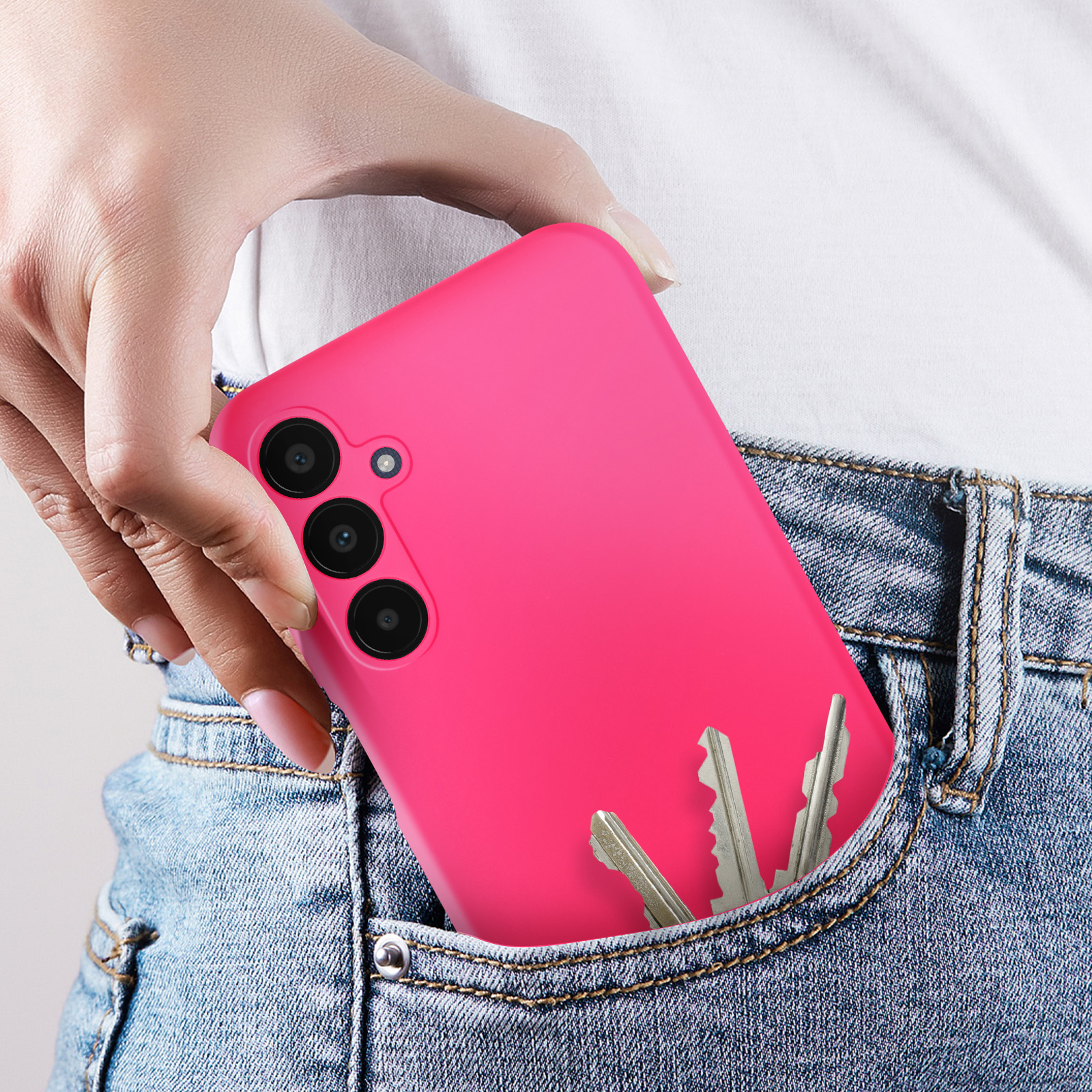 Téléphone rose dans une poche de jean avec des clés.