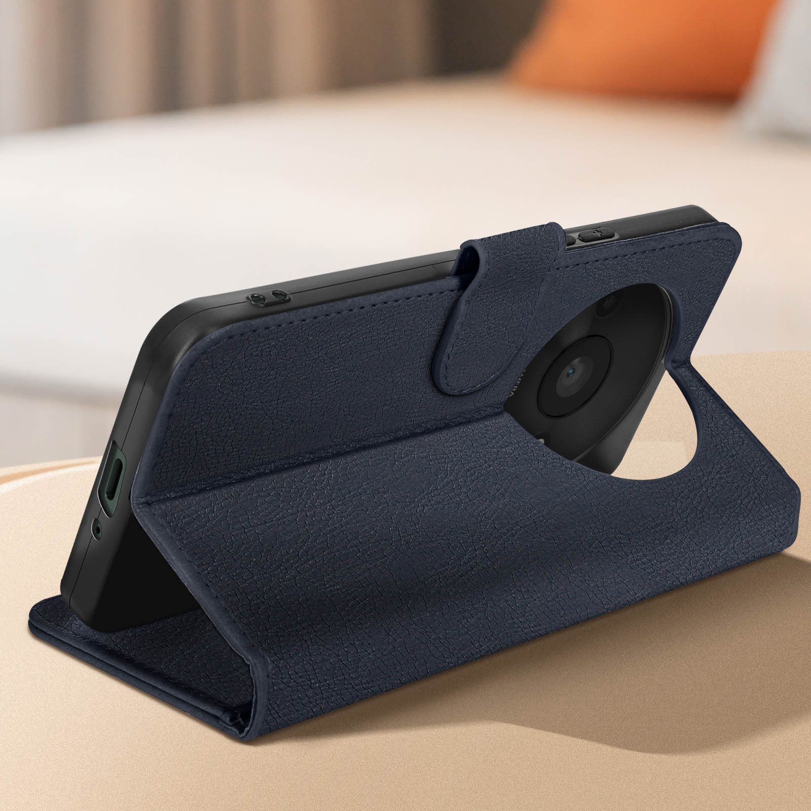 Una custodia blu per telefono è su un tavolo. Un telefono è nella custodia. Lo sfondo è un letto.