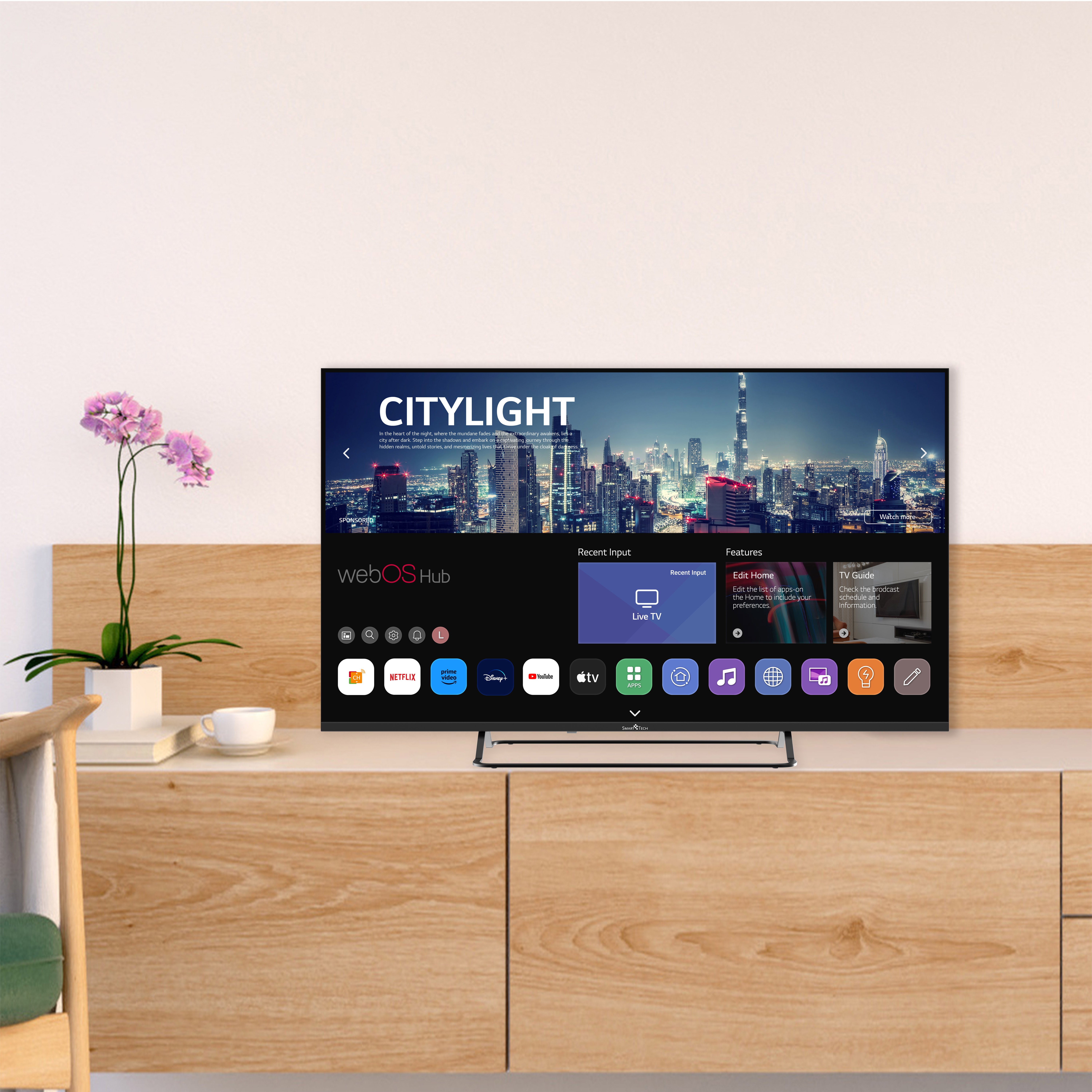 Duży nowoczesny telewizor na drewnianej szafce z interfejsem aplikacji i kwiatem.