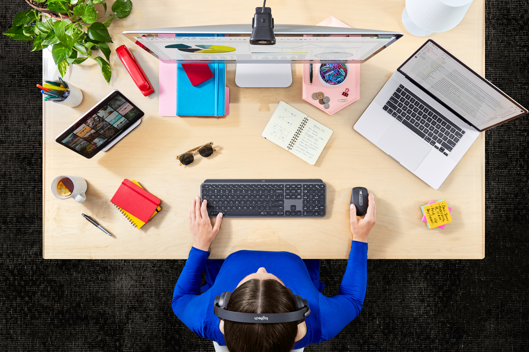 Widok z góry, kobieta przy biurku. Laptop, klawiatura, notatnik, tablet i akcesoria.