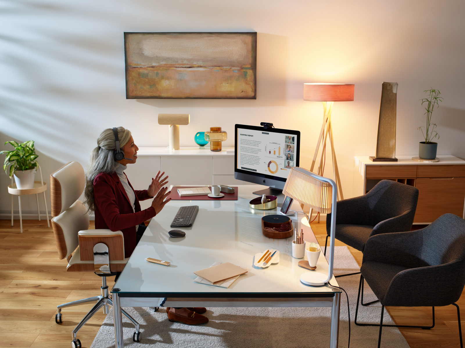 Kobieta podczas rozmowy wideo przy biurku. Widoczny komputer, światła i dekoracje.