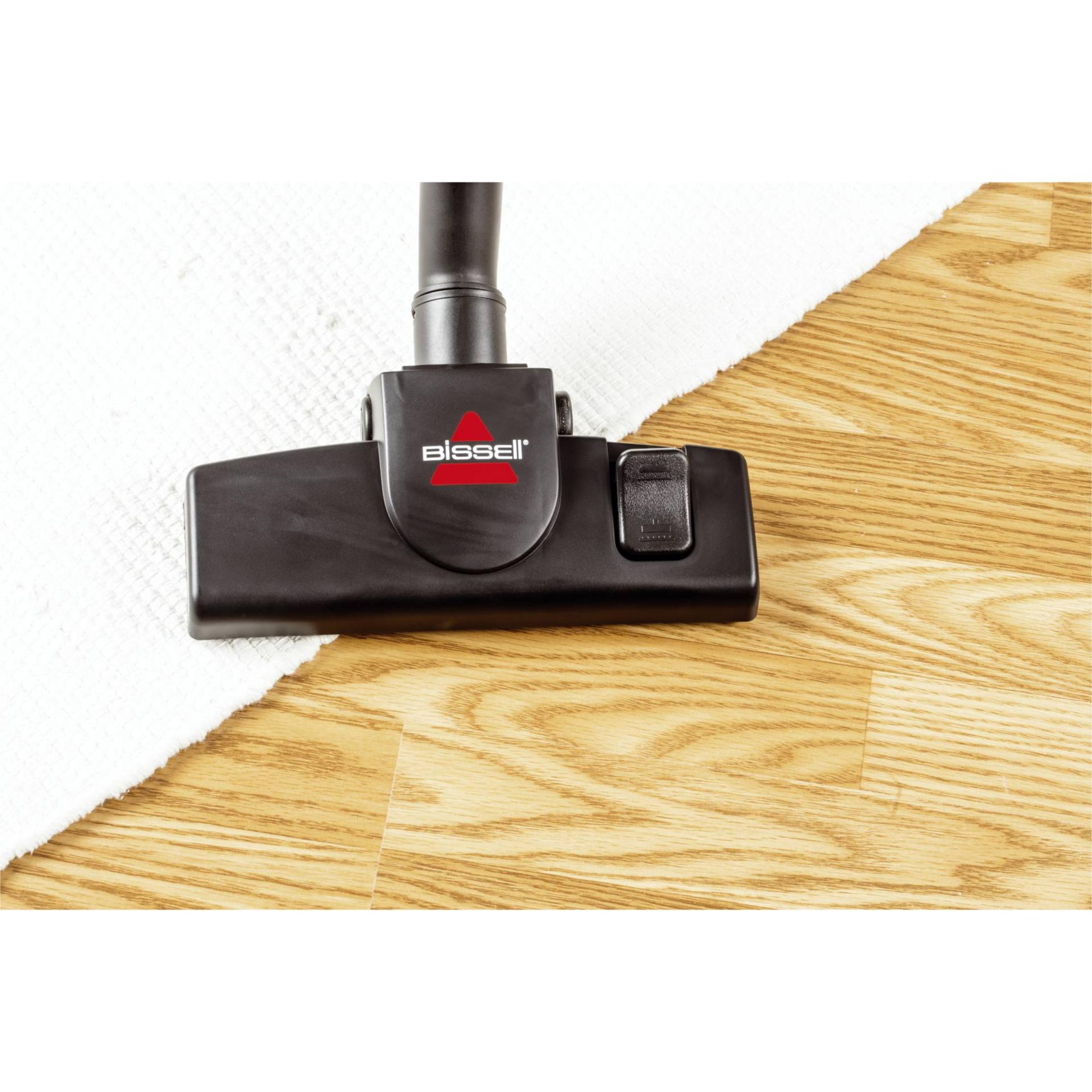 Testa dell'aspirapolvere su pavimento in legno. La testa è nera con logo rosso.
