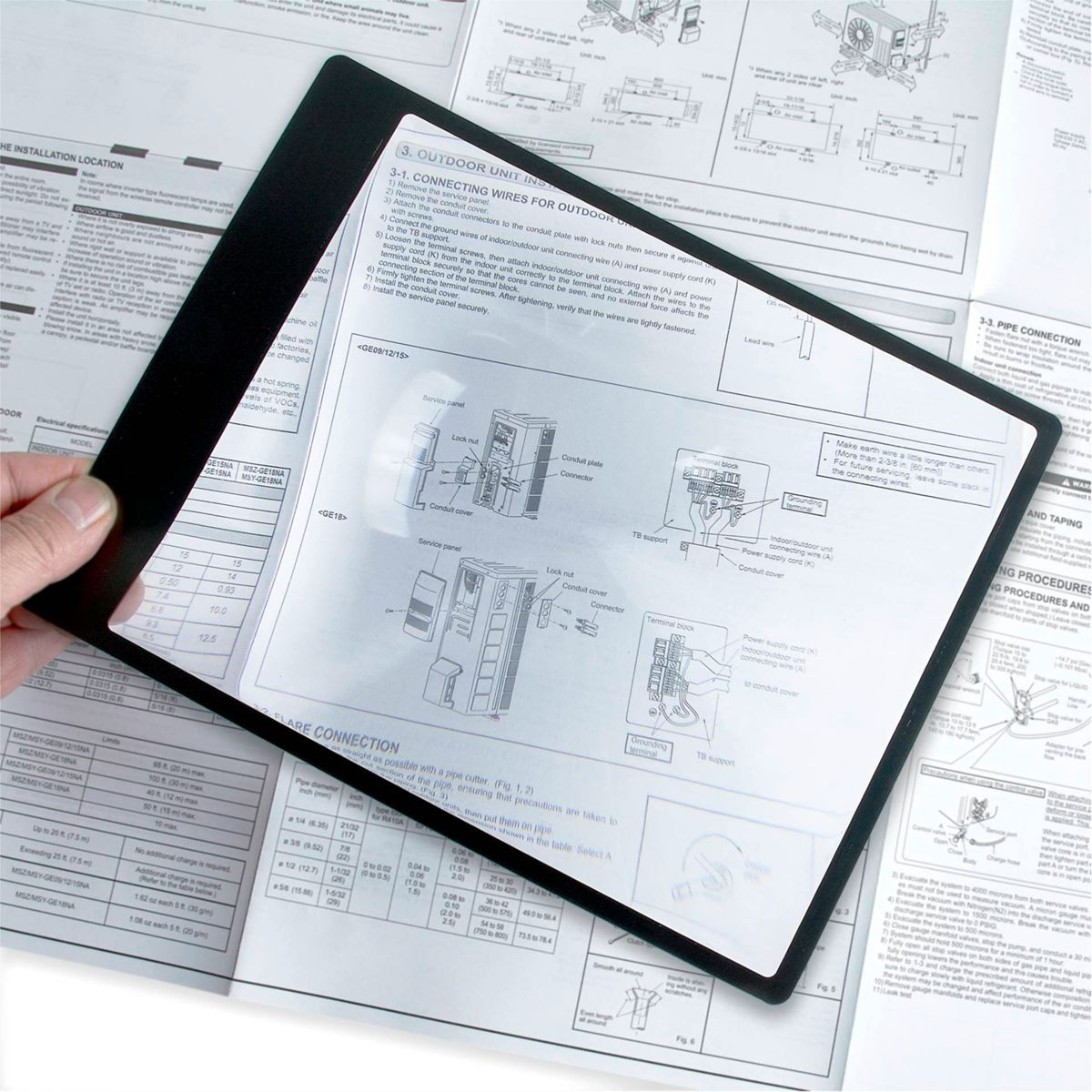 Lupe über Dokumenten, gehalten von einer Hand, Text und Diagramme sind sichtbar.