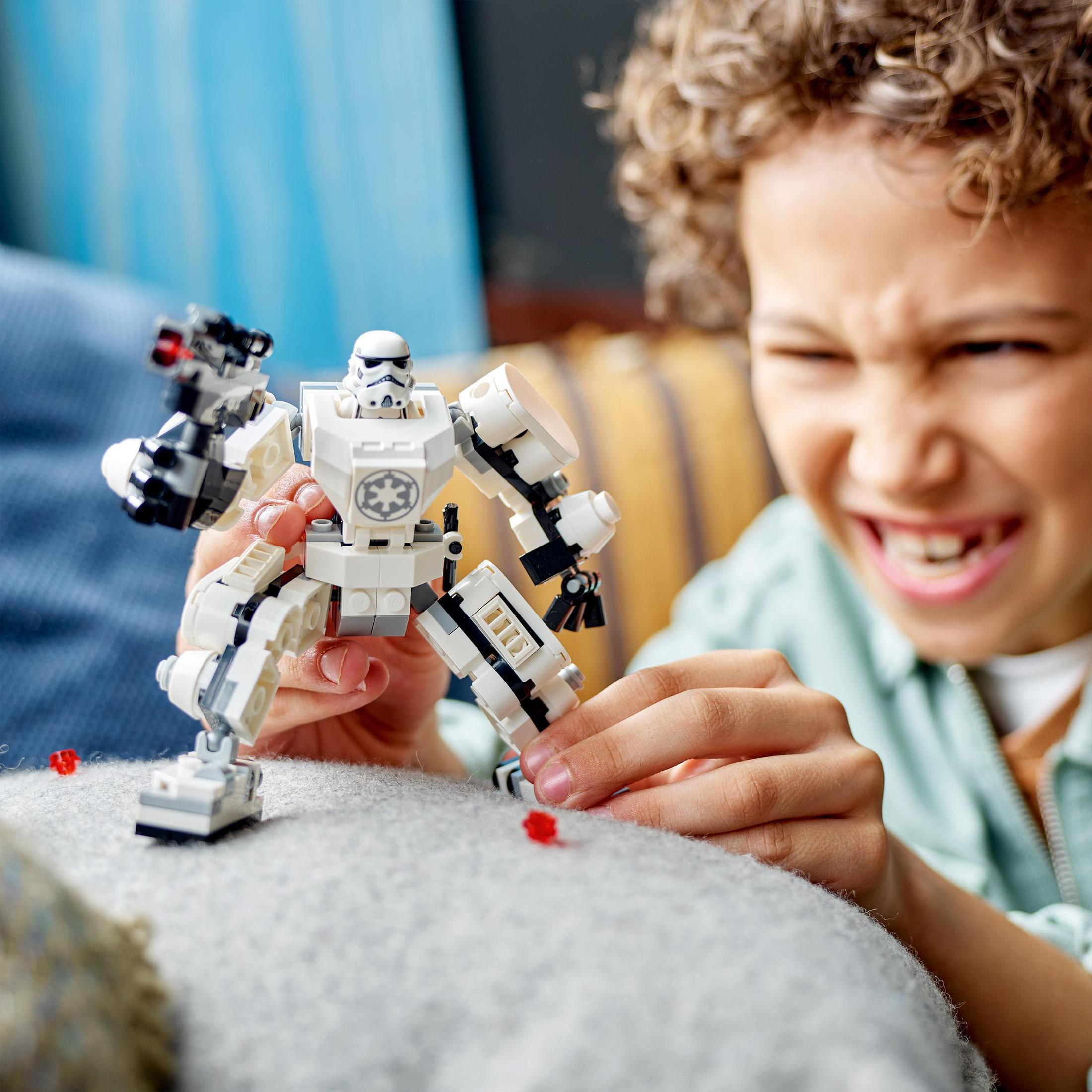 Bir çocuk Lego Stormtrooper ile oynuyor. Oyuncak beyaz ve siyah. Çocuk gülümsüyor.