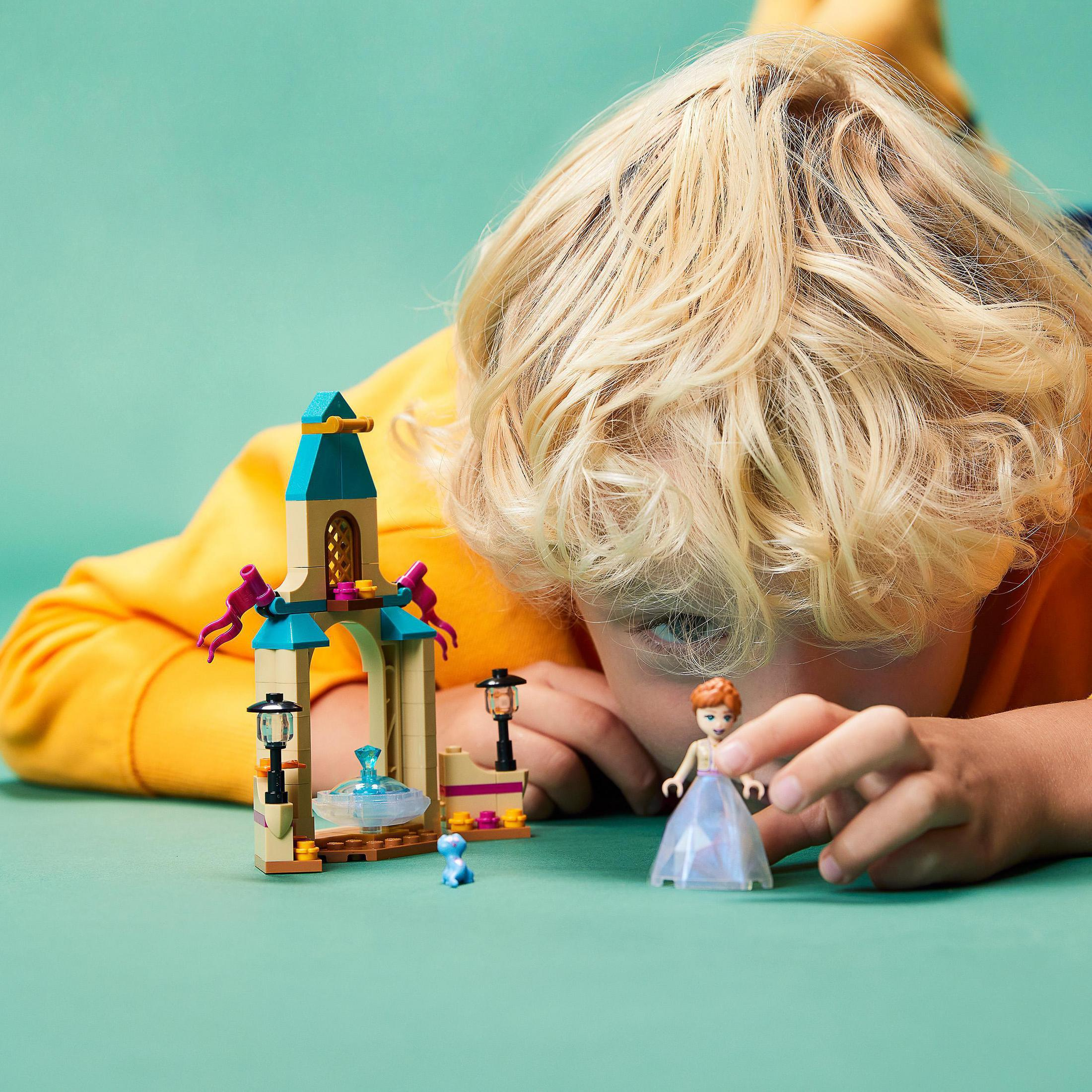 Bambino che gioca con set Lego. Un modello di castello Lego con fontana e un personaggio Lego.