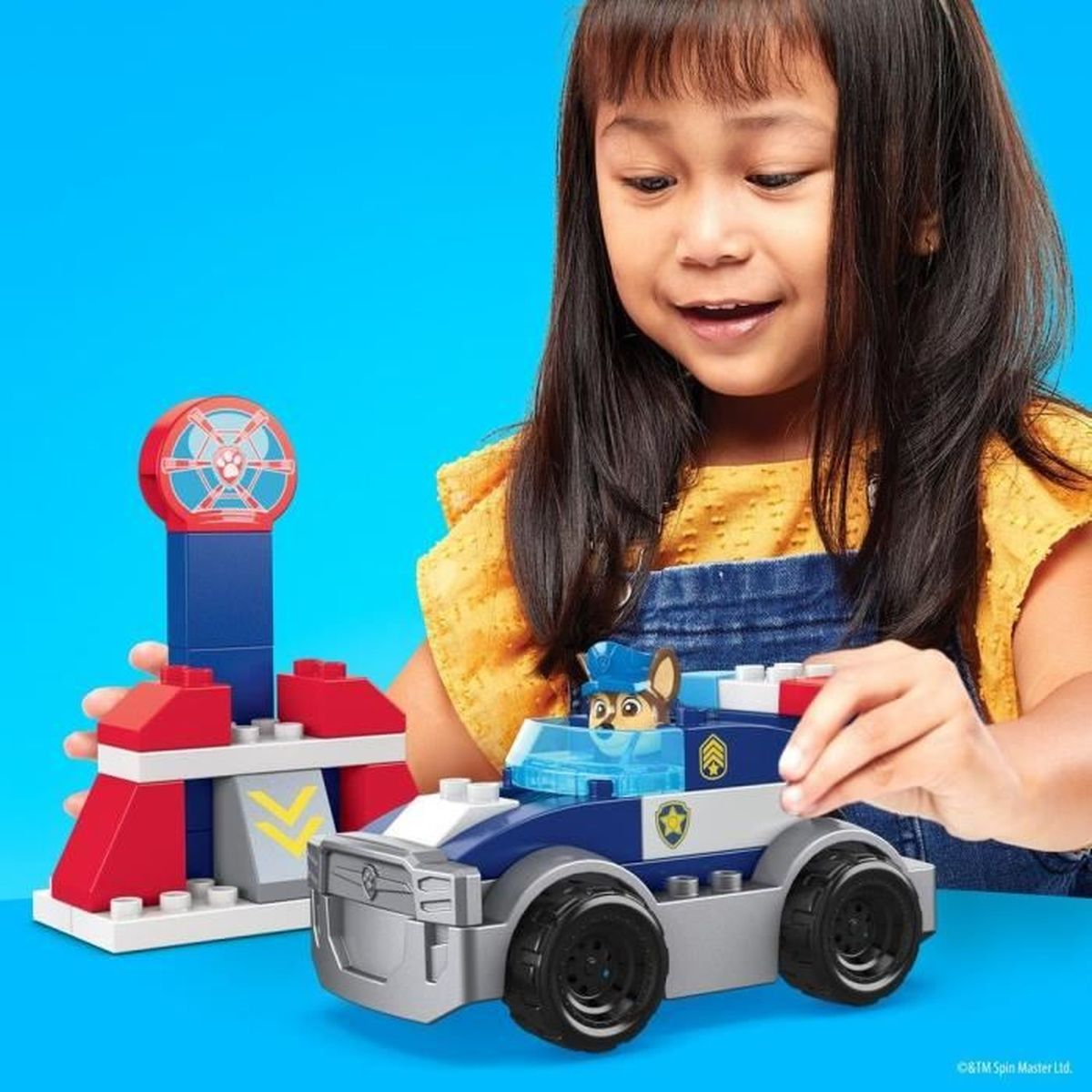 Bambina che gioca con un'auto della polizia giocattolo e blocchi.