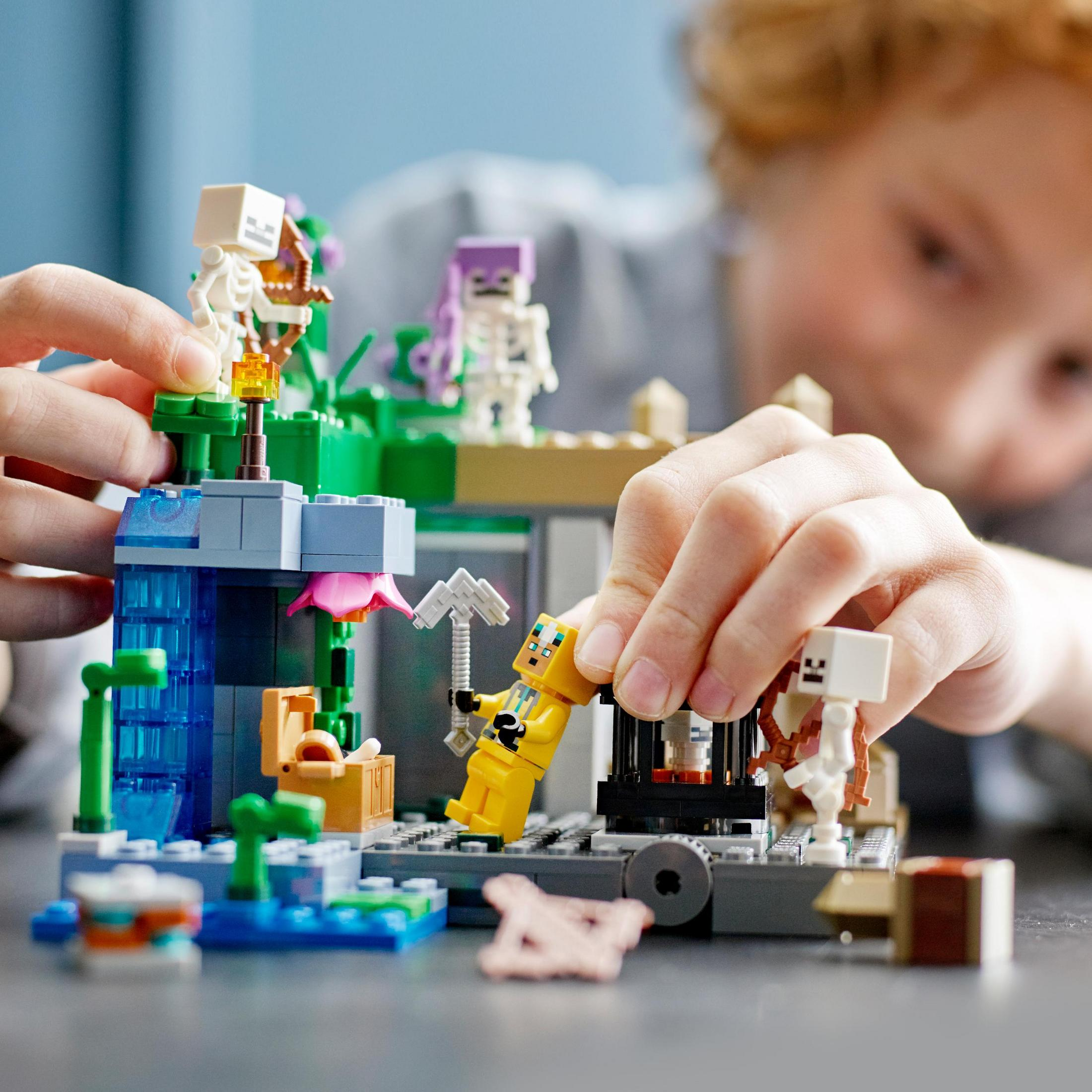Eine Person spielt mit einem LEGO Minecraft-Set mit mehreren Figuren und Elementen.