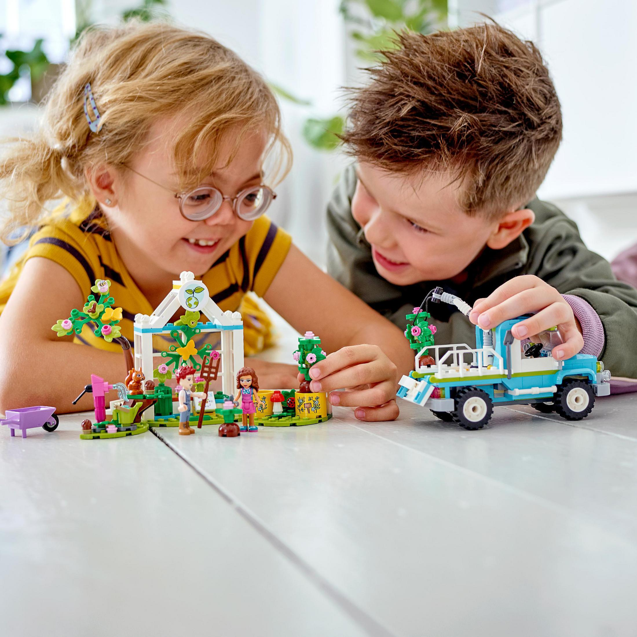 Zwei Kinder spielen mit Lego. Einer mit einem Lastwagen, der andere mit einem Hausmodell.