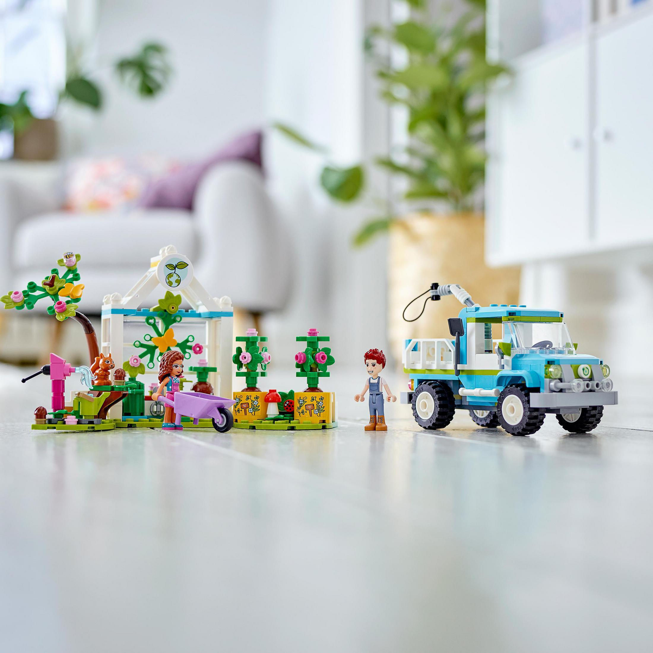LEGO Friends Set mit Gewächshaus, LKW und Minifiguren. Helle Farben, Szene im Freien.