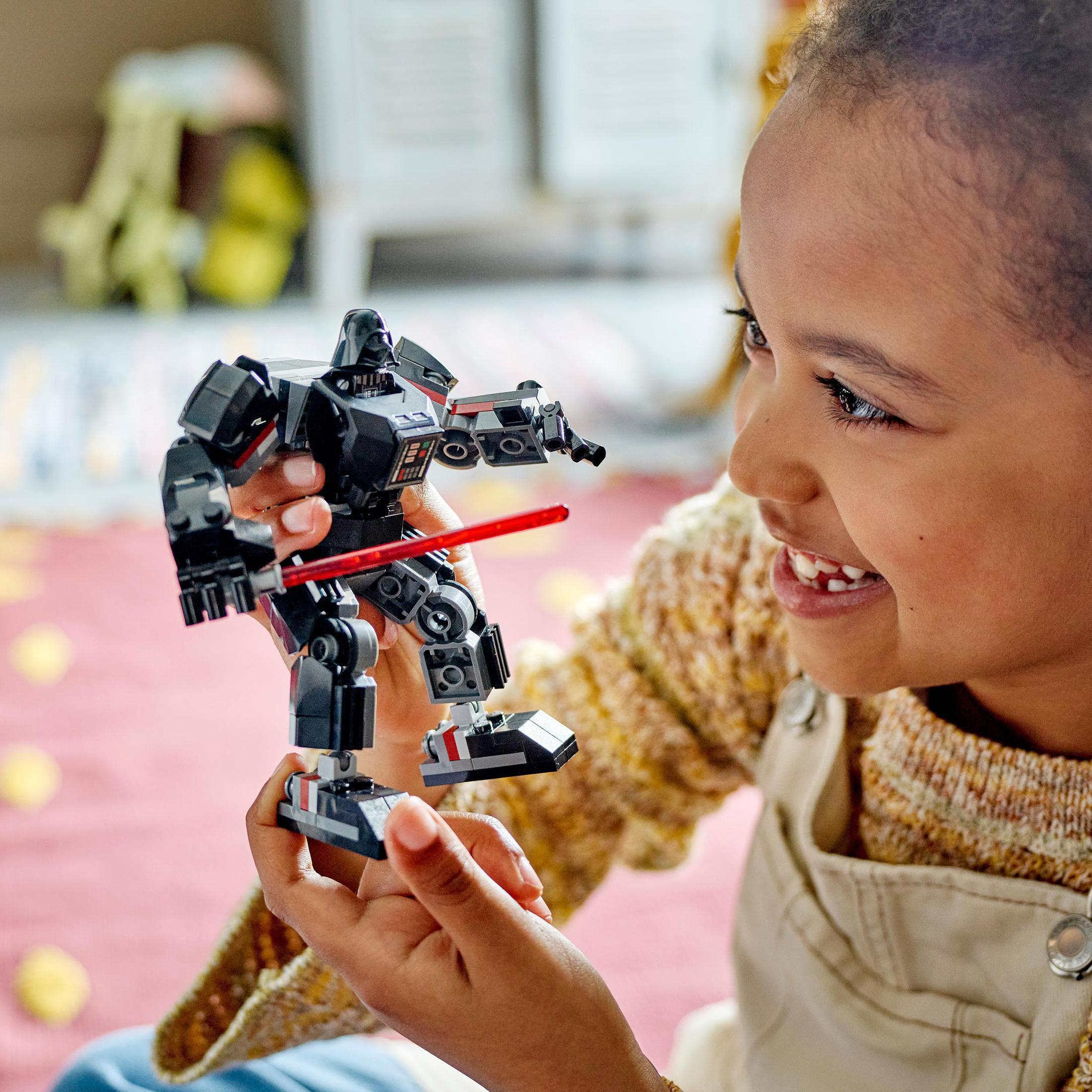 Ein Mädchen hält eine Lego-Figur. Die Figur ist ein schwarzer Roboter mit rotem Licht.