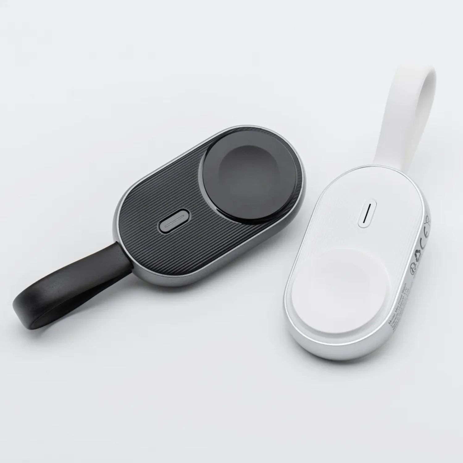 Zwei schwarz-weiße Apple Watch-Ladegeräte. Eines schwarz, eines weiß, mit Schlaufe.