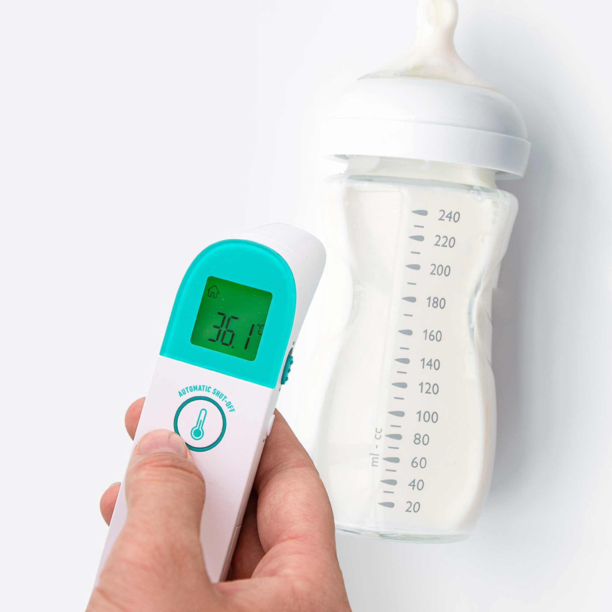 Eine Hand hält ein Thermometer auf eine Babyflasche. Das Thermometer zeigt 36,1 Grad an.