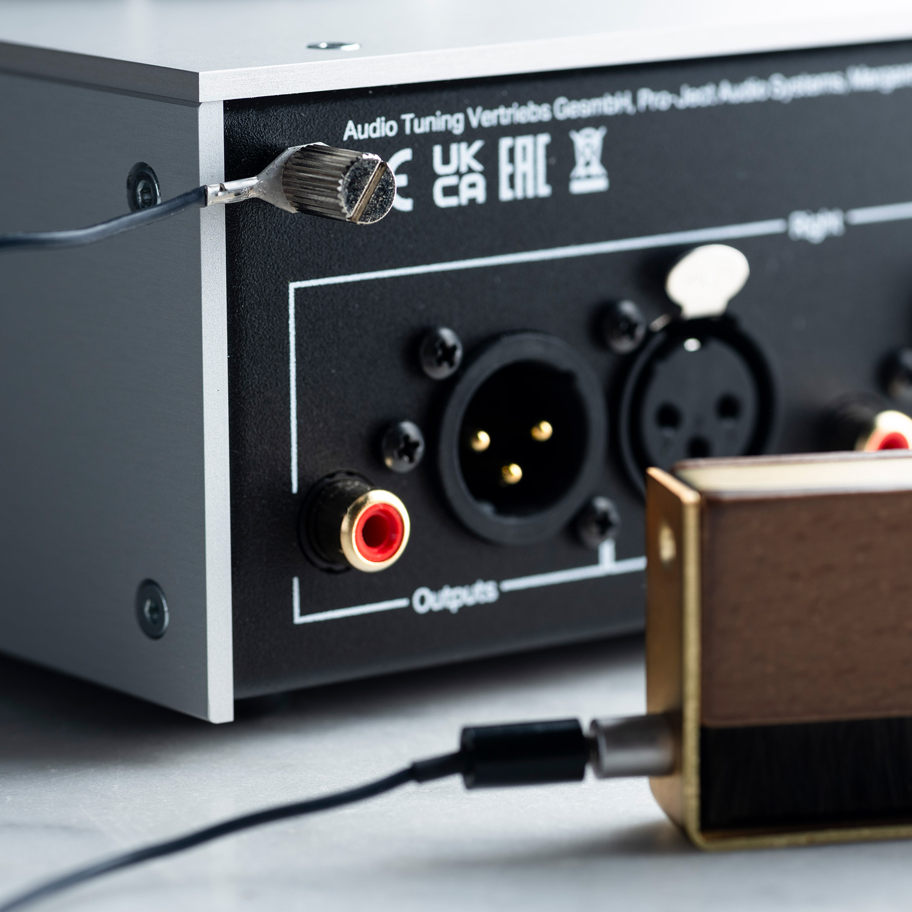 Połączenia sprzętu audio. Srebrny element ze złotymi i czarnymi złączami oraz podłączonymi kablami.