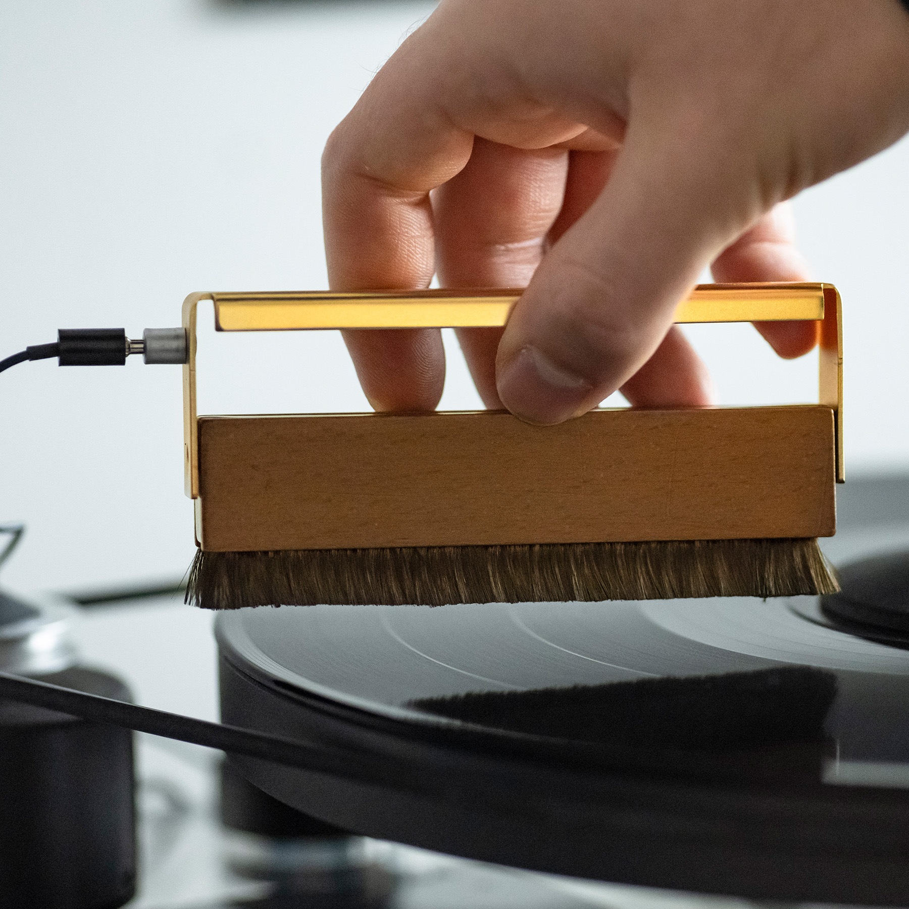 Ręka używająca szczotki na płycie. Złota szczotka z czarnym kablem.