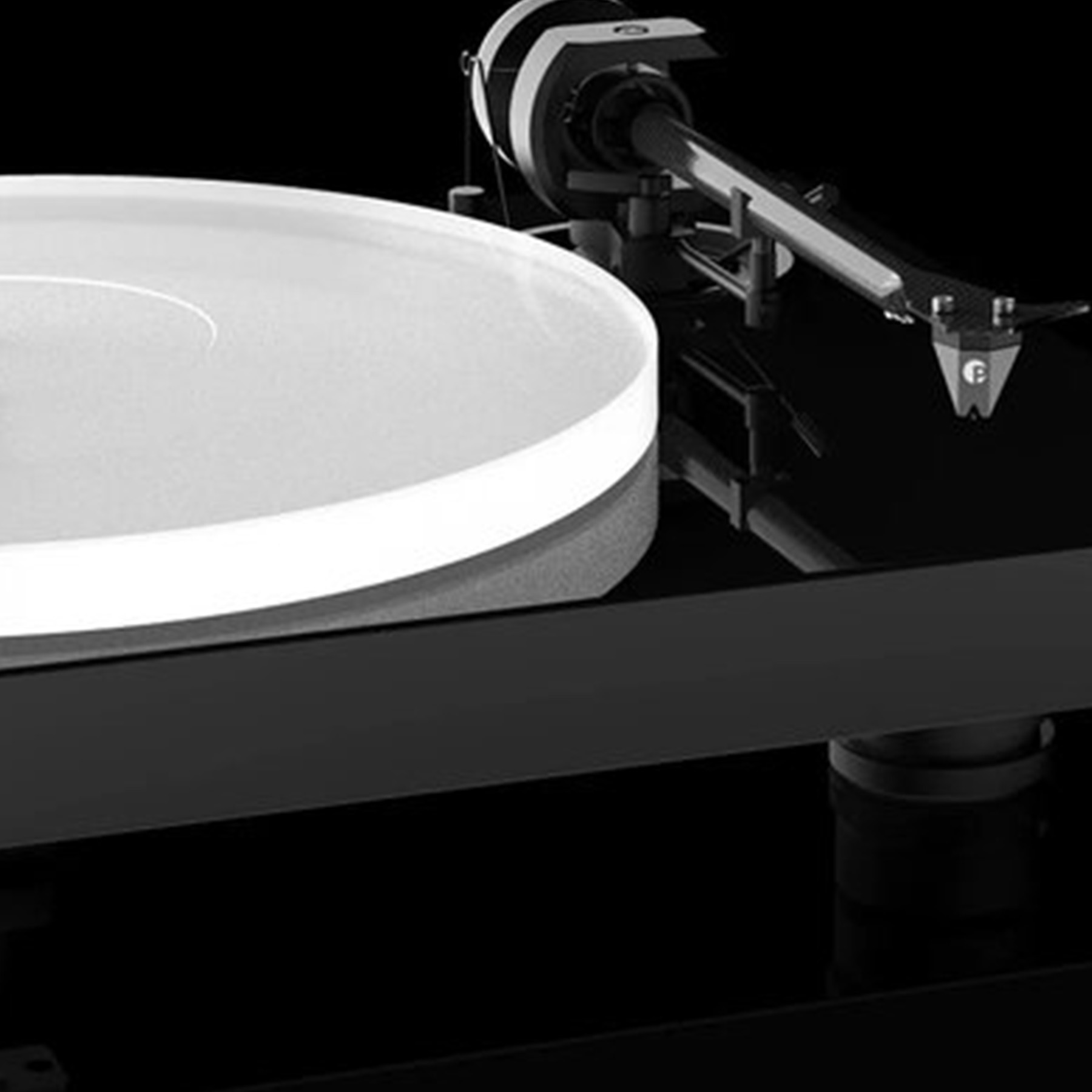 Gramofon, czarny, z białym dyskiem i czarnym ramieniem. Czarne tło.