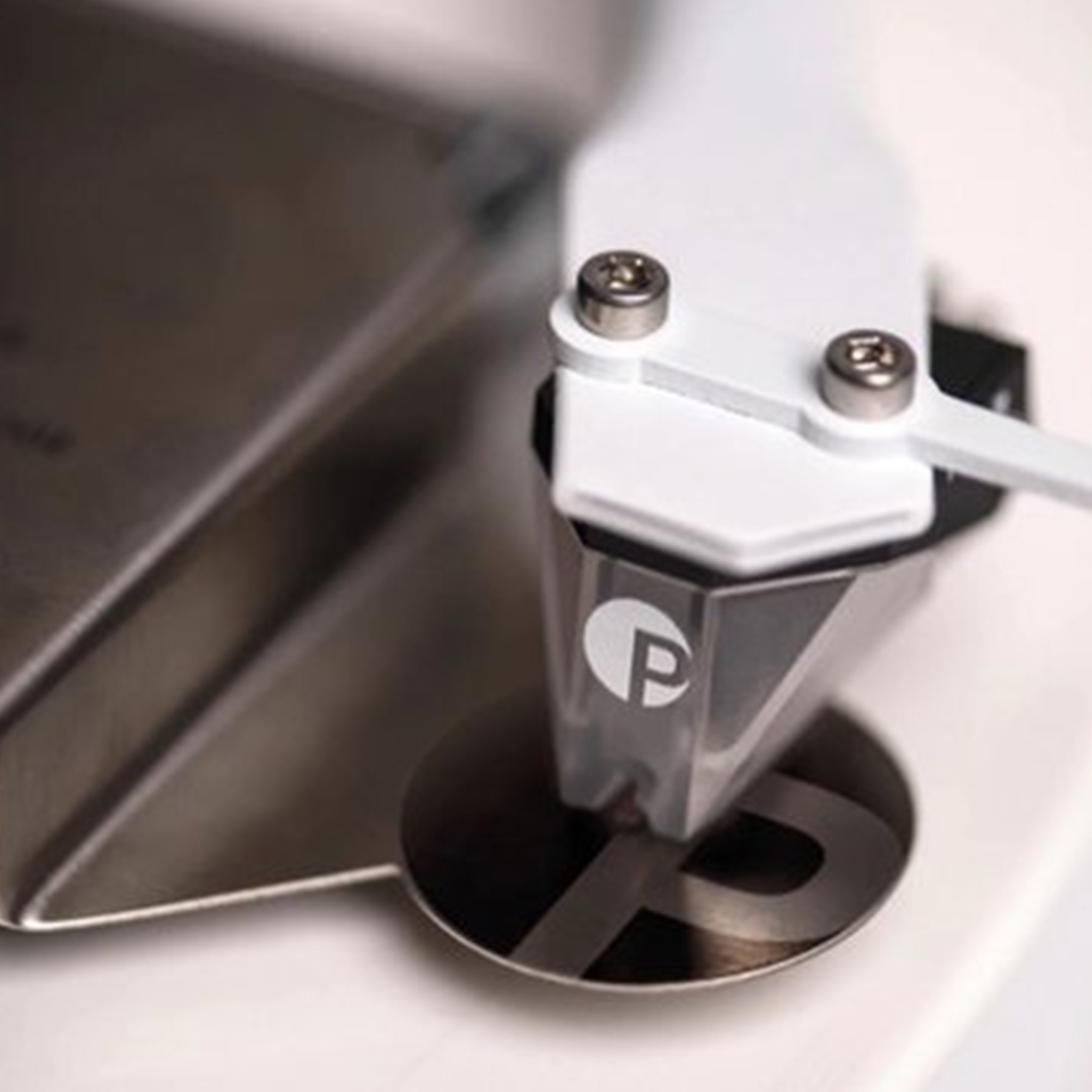 Zbliżenie igły gramofonowej na płycie winylowej. Igła ma logo.