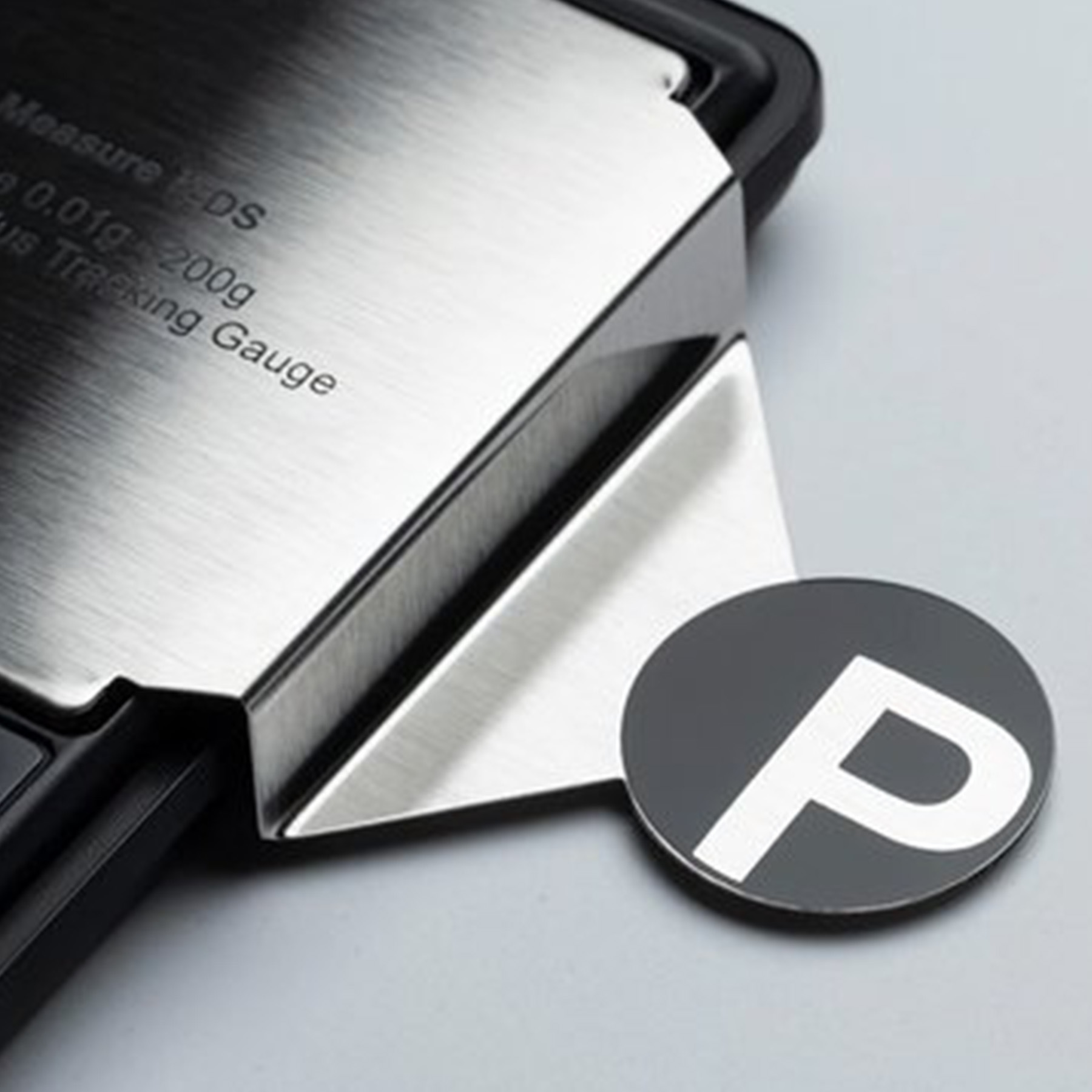 Zbliżenie wagi. Litera P w okręgu po prawej stronie.