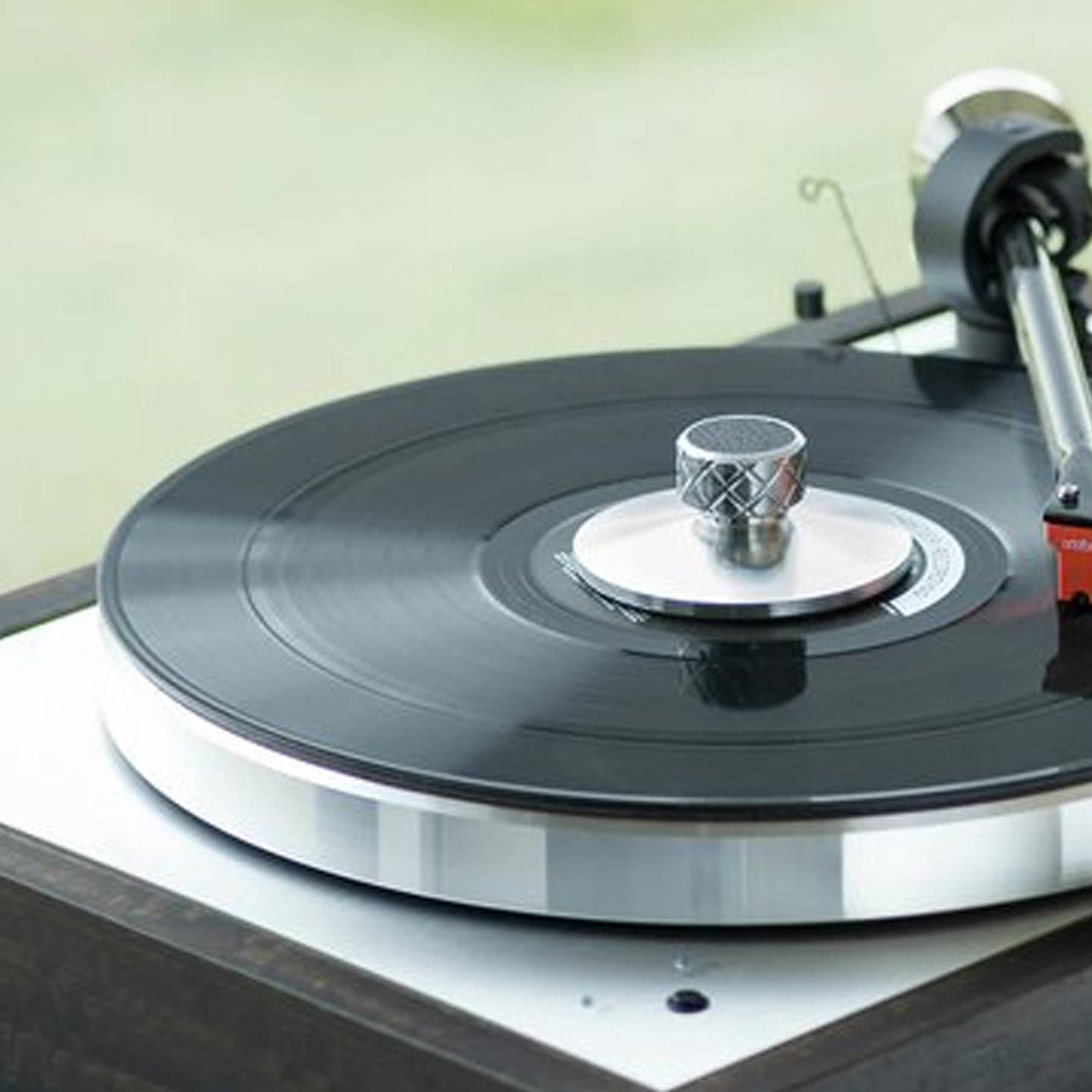 A turntable, with a black record playing, and a chrome-colored arm.
