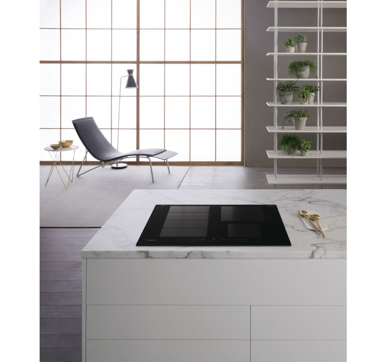 Cuisine moderne avec une table de cuisson sur un comptoir blanc. Grandes fenêtres et design minimaliste.