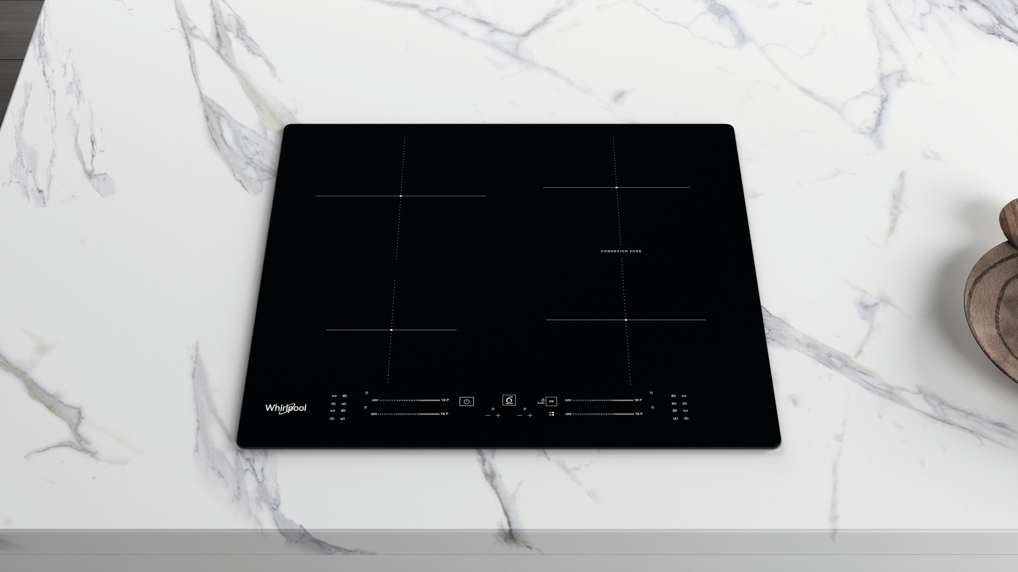 Un piano cottura a induzione Whirlpool nero su un piano di lavoro in marmo bianco.
