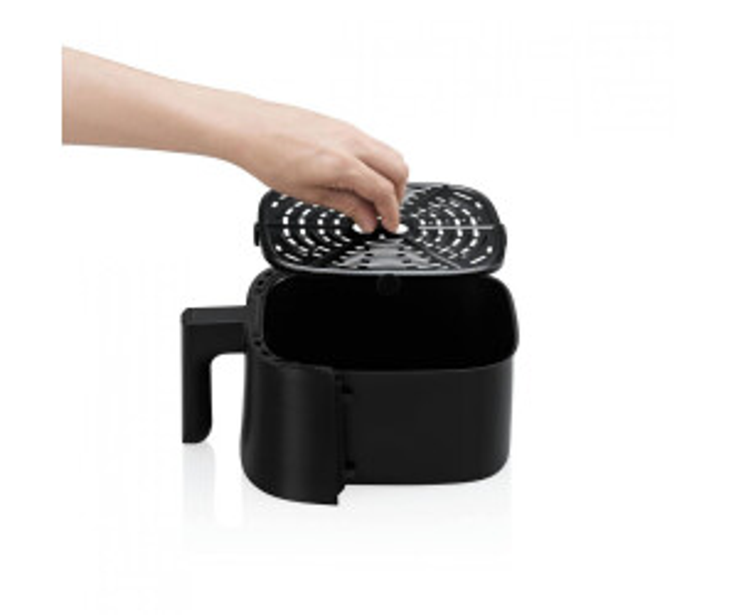 Frytownica powietrzna z otwartą pokrywą. Ręka nakłada pokrywę. Czarny korpus i uchwyt.