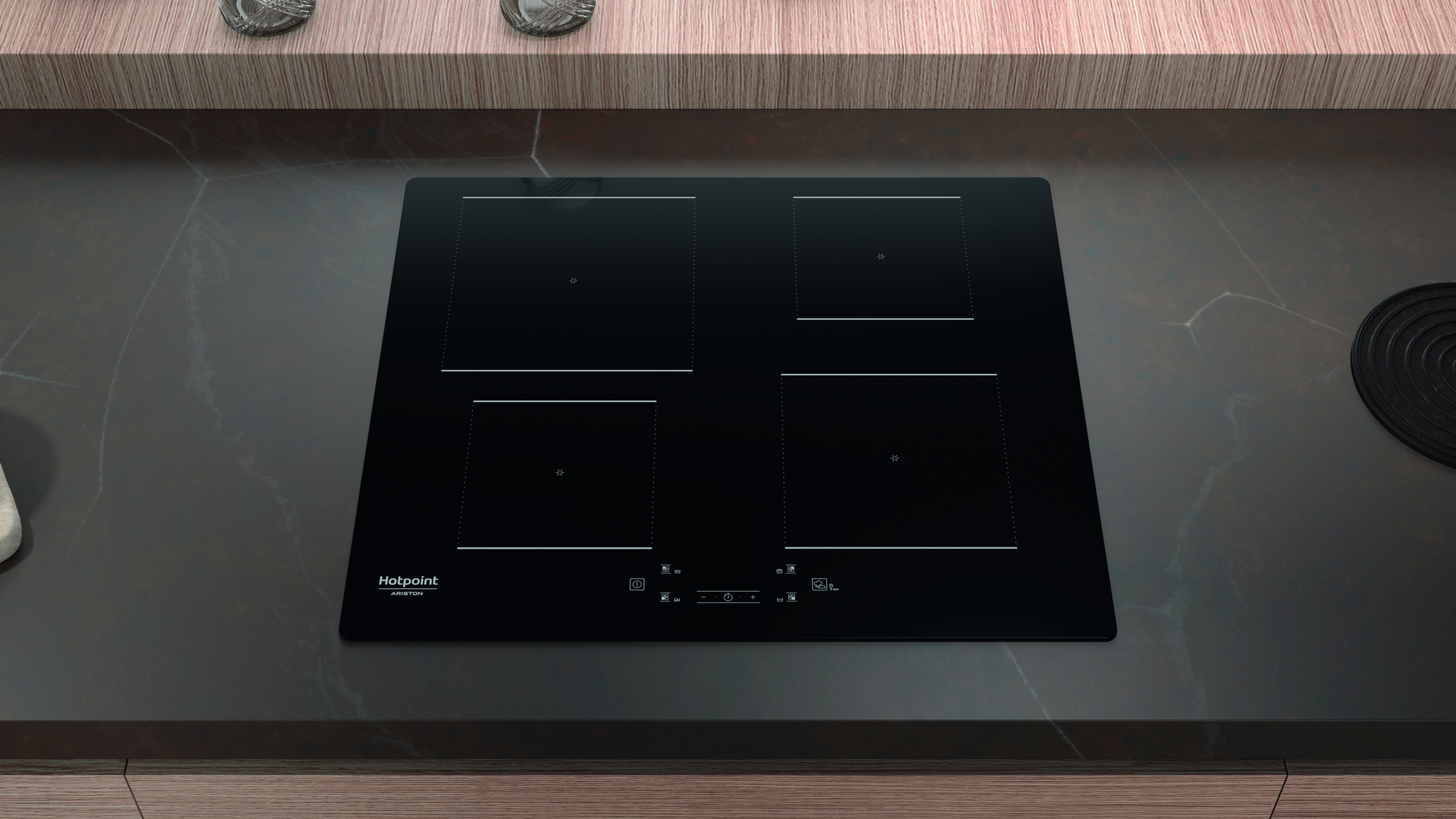 Czarna, wbudowana płyta indukcyjna z czterema palnikami, na ciemnym blacie.