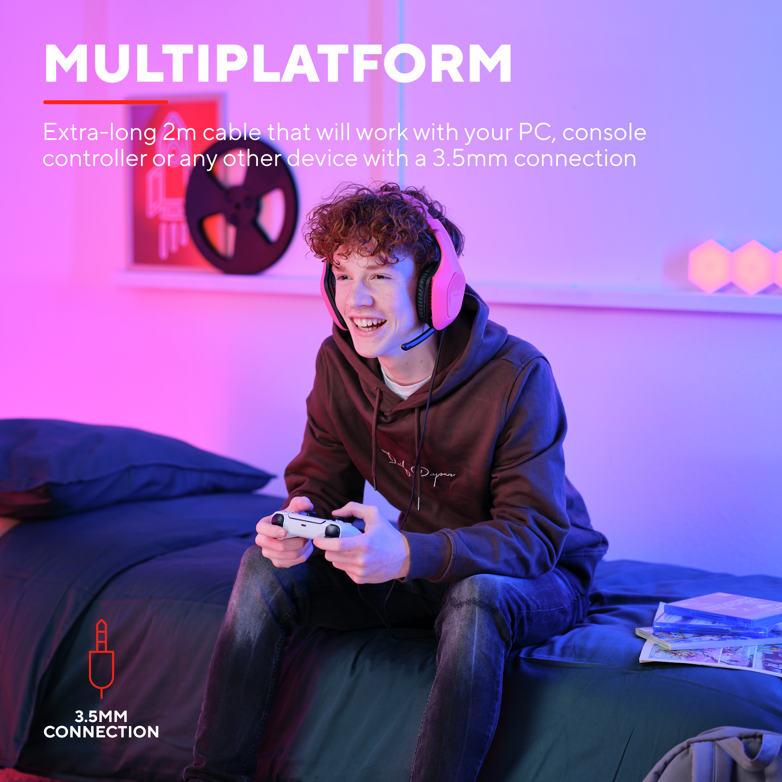 Un jeune homme portant un casque rose, tenant une manette de jeu blanche, souriant.